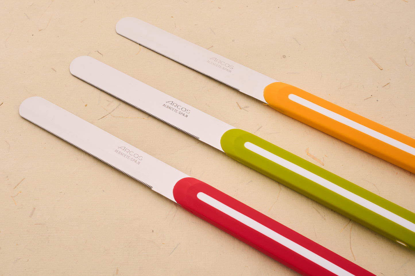 Arcos Linea 3pc Table Knife Set with serrated blades and colorful handles, showcasing Spanish craftsmanship on a neutral backdrop.
