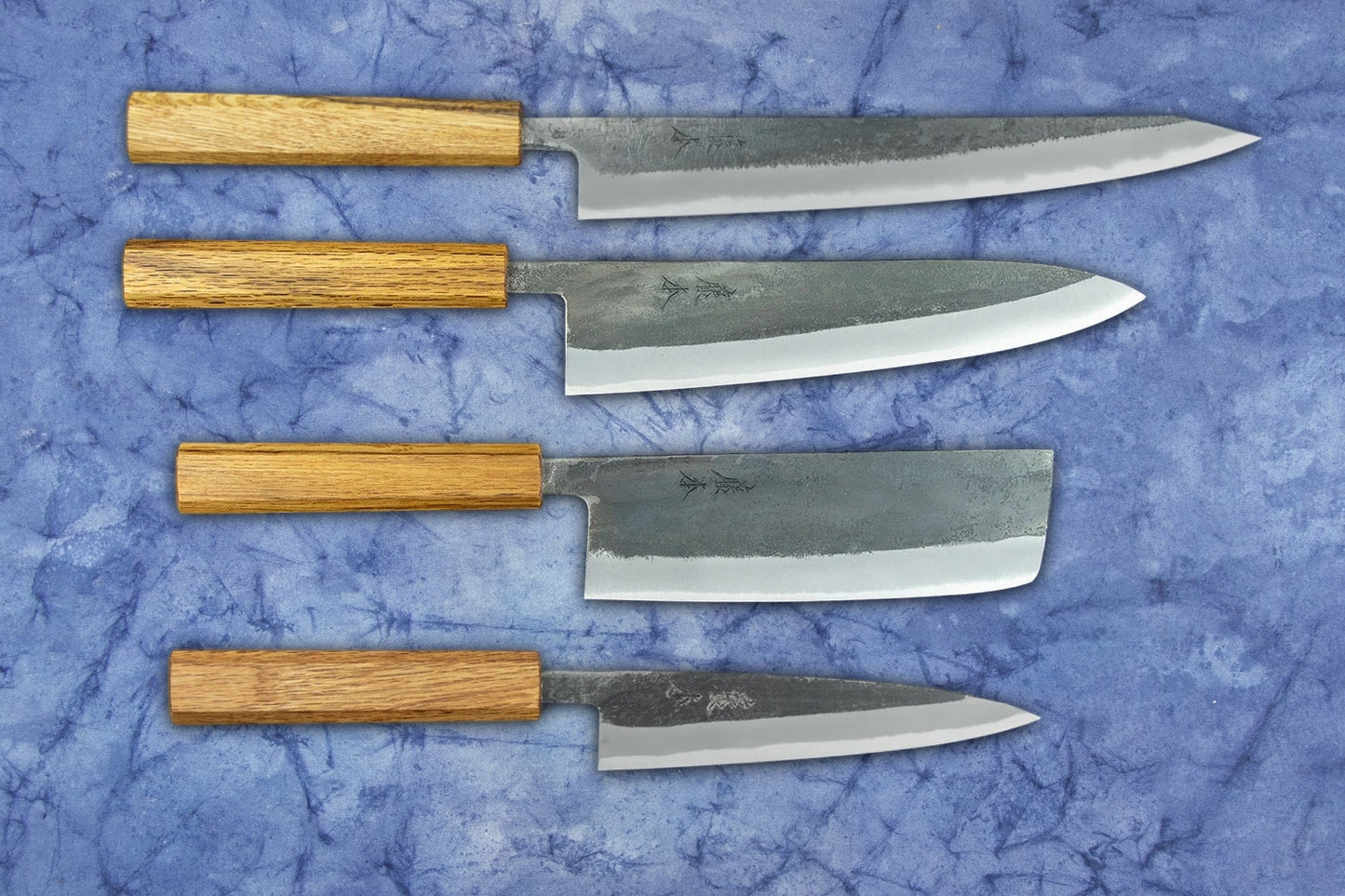 Fujimoto Kurouchi-Forged 4 Piece Knife Set showcasing artisan-made Japanese kitchen knives: yanagiba, gyuto, nakiri, and petty, with hand-forged carbon-steel blades and straight-grained wooden handles.