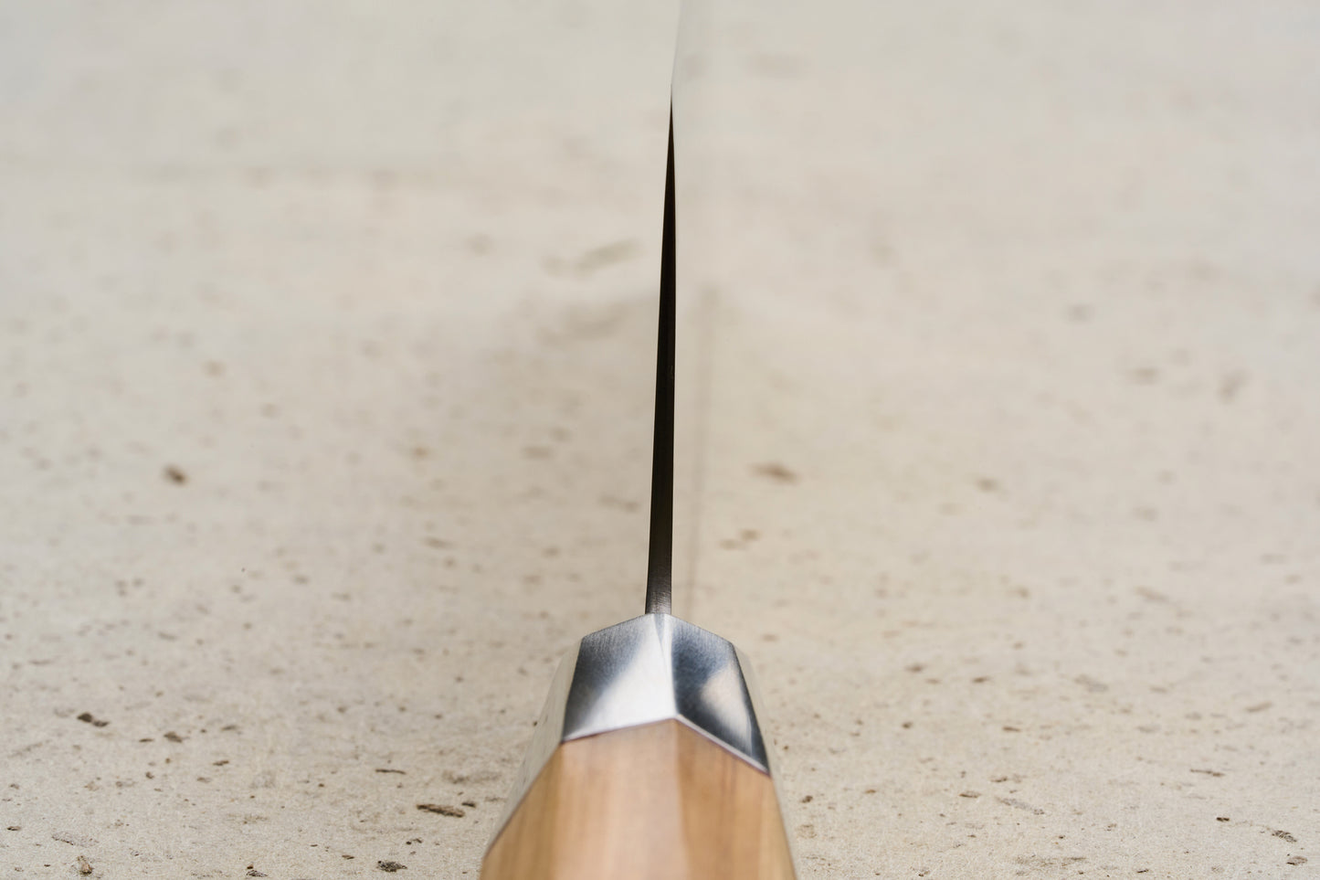 Mcusta Zanmai Beyond Nakiri 165mm knife on a stone surface, showcasing its thin blade and elegant Hinoki wood handle with polished metal bolster, embodying precision and luxury from Seki City's renowned craftsmanship.