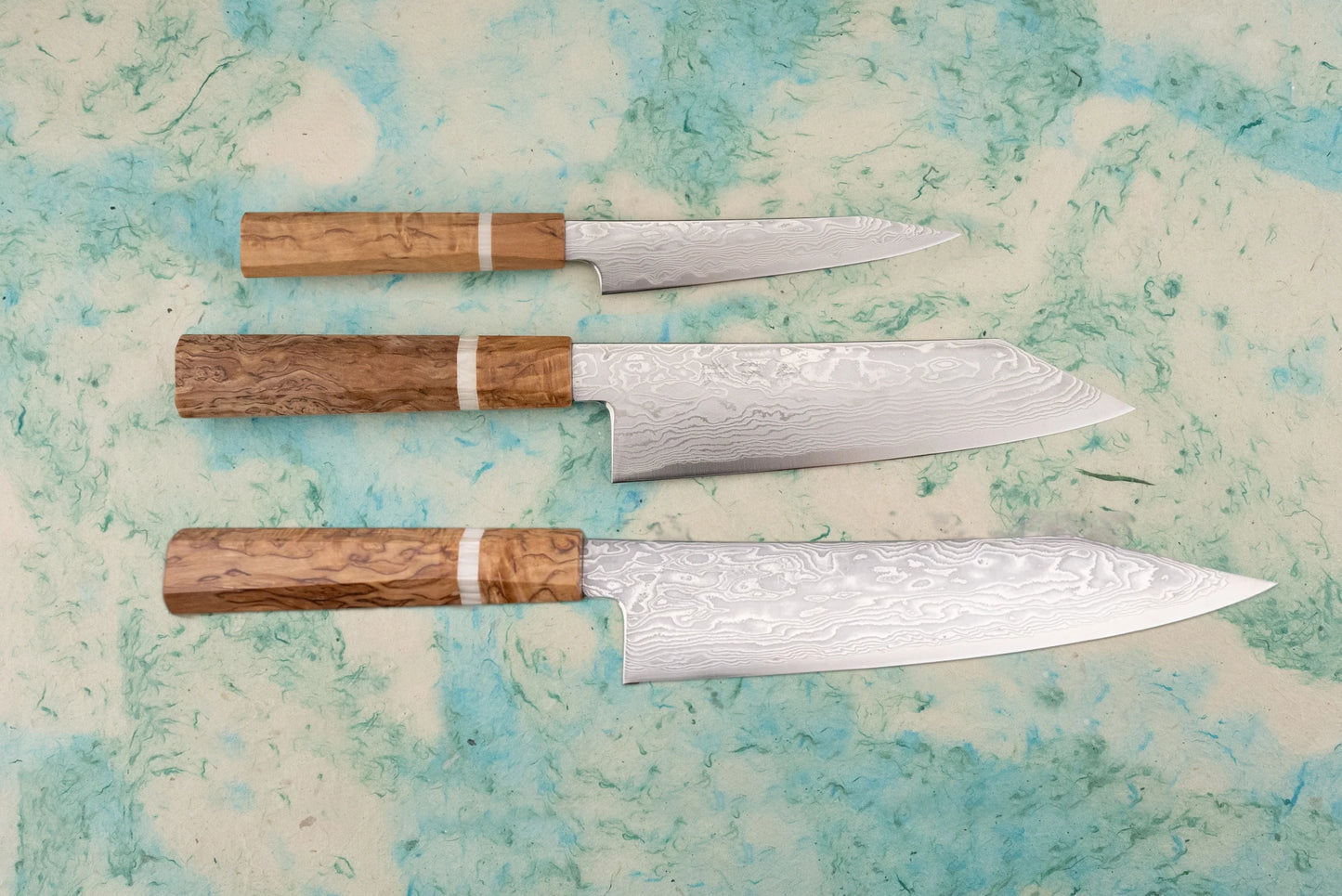 Ryusen Fukakuryu KAI 3 Piece Knife Set featuring hand-forged Damascus steel blades and octagonal wooden handles, showcasing a gyuto, santoku, and larger chef’s knife, perfect for precision cutting.