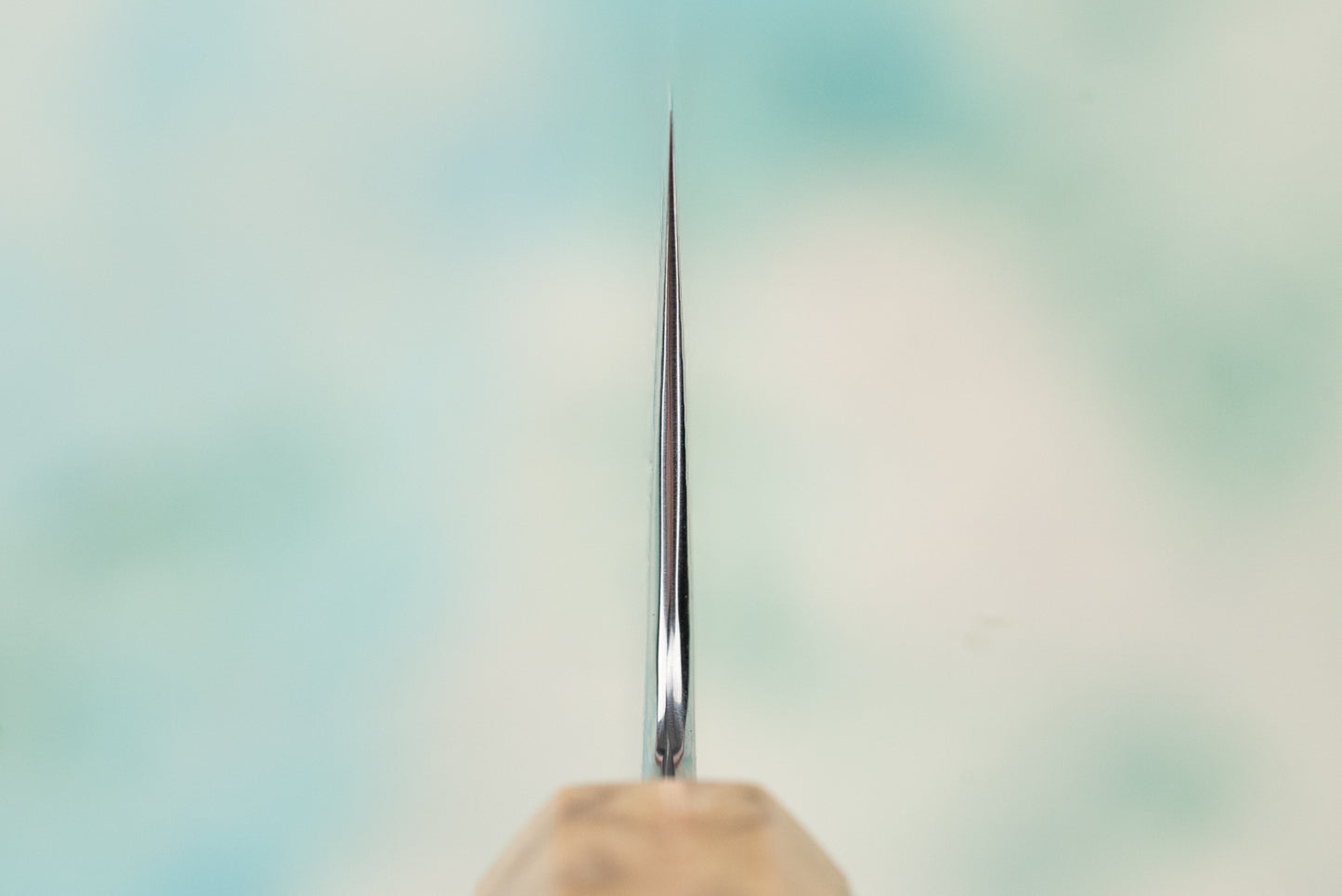 Close-up of Ryusen Fukakuryu KAI Gyuto 210mm knife, showcasing its razor-thin edge and wooden handle, highlighting the precision craftsmanship of this expertly forged Japanese kitchen tool.