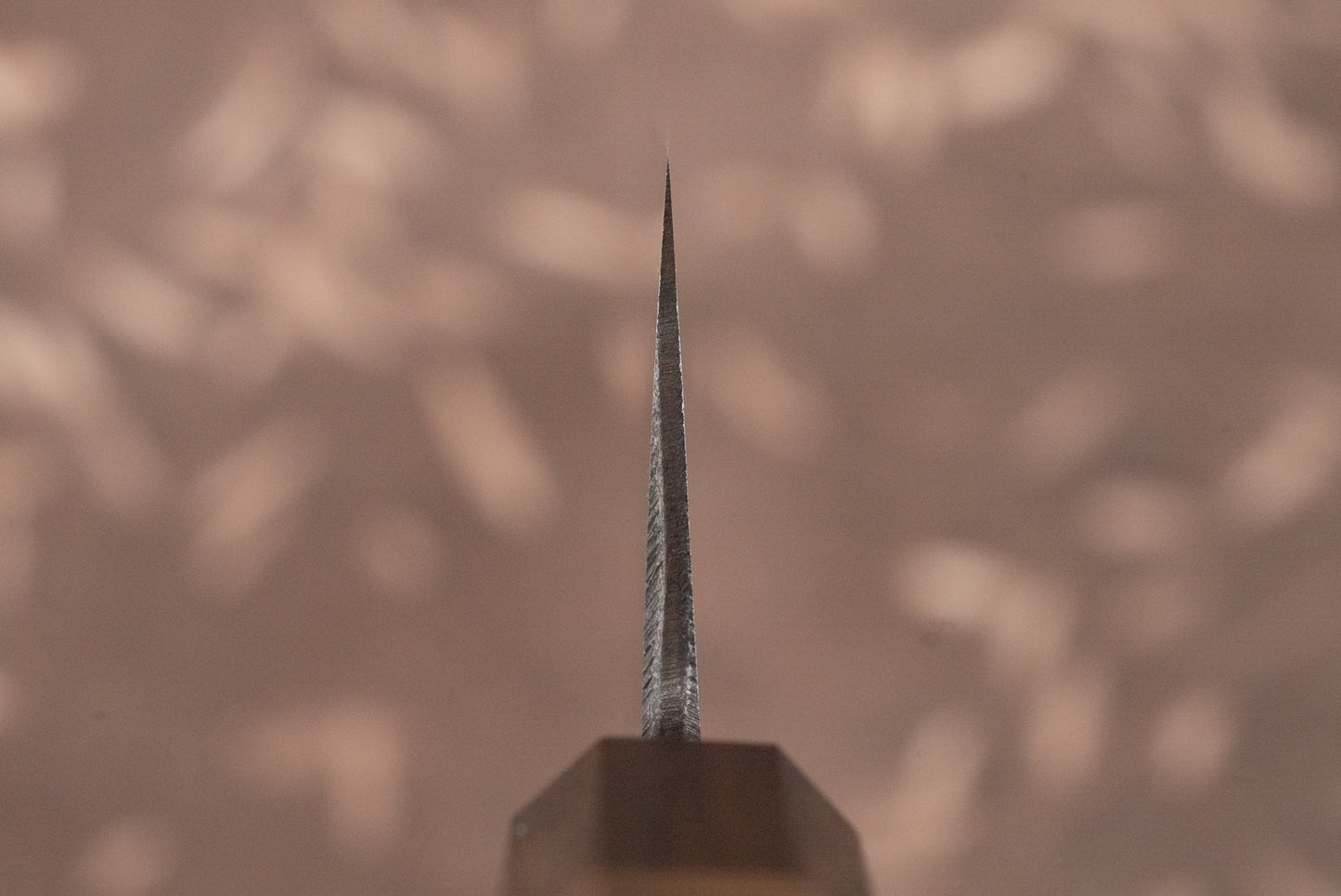 Tight close-up of the Touroku Sakai Aogami Damascus Kiritsuke Santoku 180mm knife blade edge, showcasing precision craftsmanship with its sleek design and visible handle, embodying Japanese knifemaking expertise.