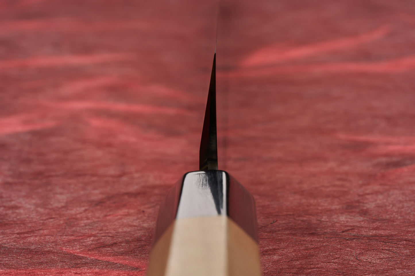 Touroku Sakai Tohwa Shirogami Yanagiba 270mm, a Japanese-style kitchen knife with an octagonal wooden handle, elegantly laid on a red surface, showcasing its single-bevel blade designed for precise slicing.