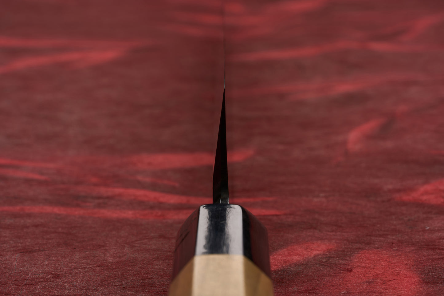 Touroku Sakai Tohwa Shirogami Kiritsuke Yanagiba 270mm knife, featuring a wooden octagonal grip and metal bolster, rests on a red cloth, showcasing its precision-crafted spine and craftsmanship.