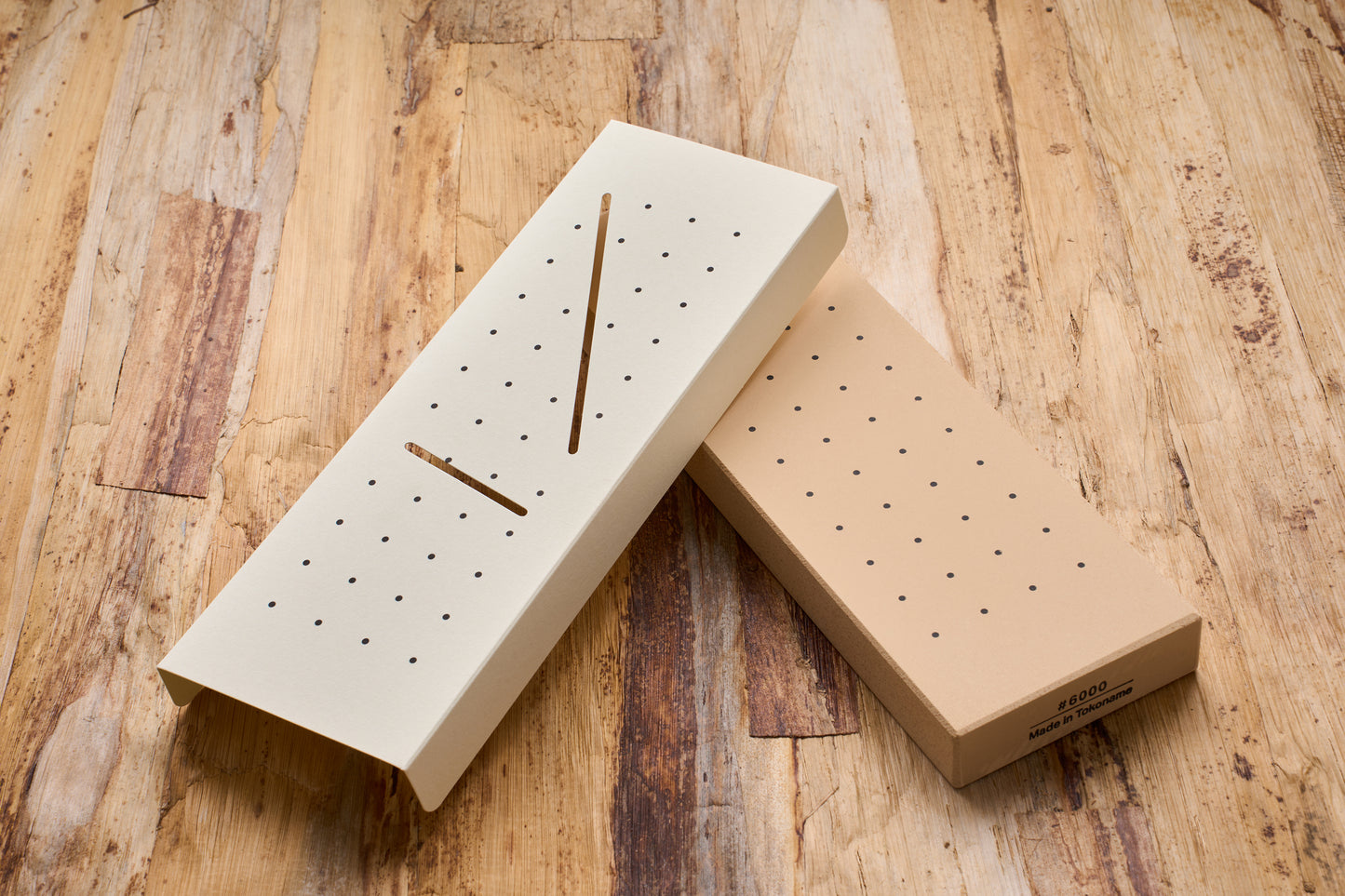 10 Good Fine 6000 Grit Stone with perforated flattening plate on a table, showcasing its tactile guidance feature for sharpening beginners.