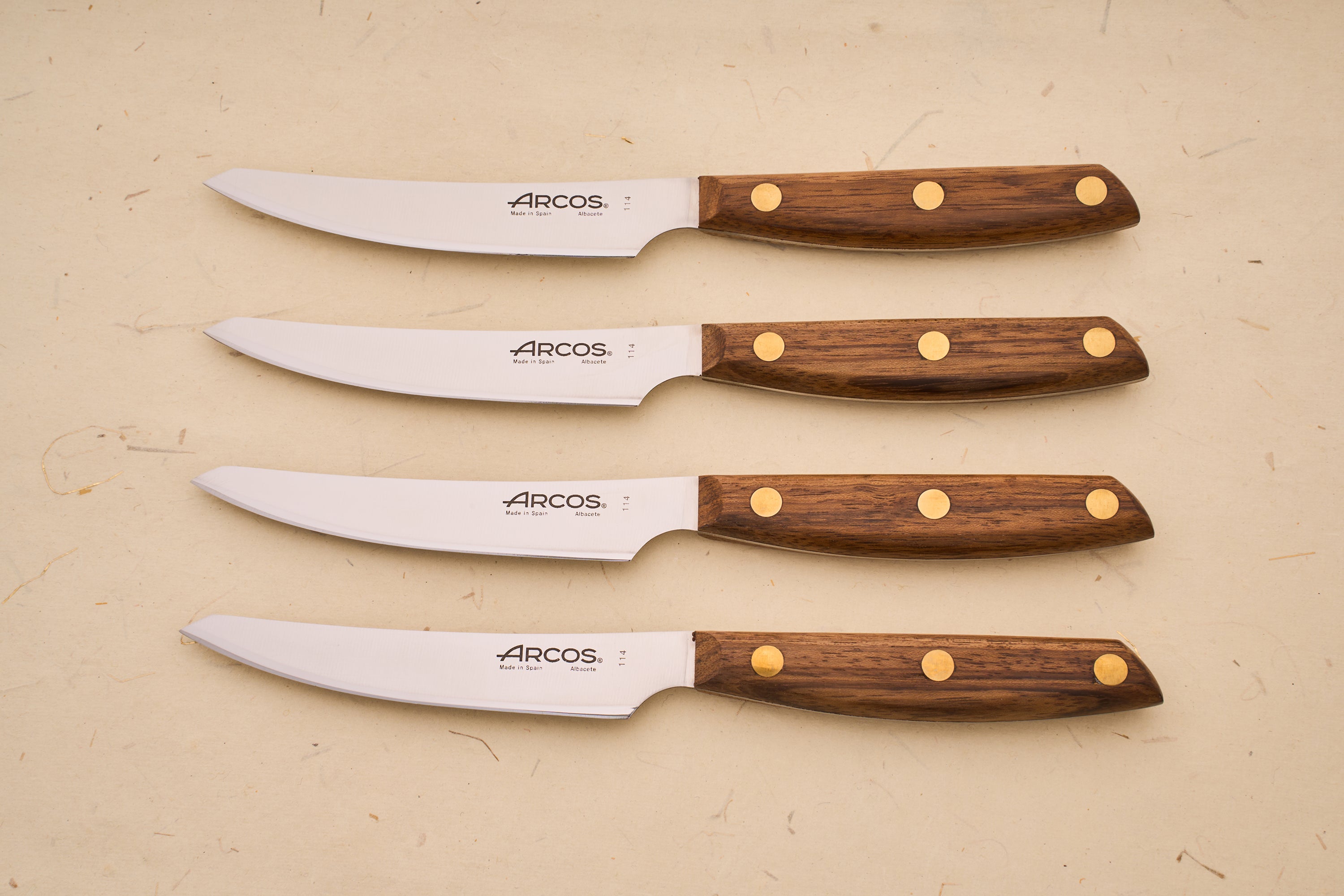 Arcos Nordika 4pc Steak Knife Set with stainless-steel blades and dark wood handles, crafted in Spain, showcasing precision and quality from a historic knife-making legacy.