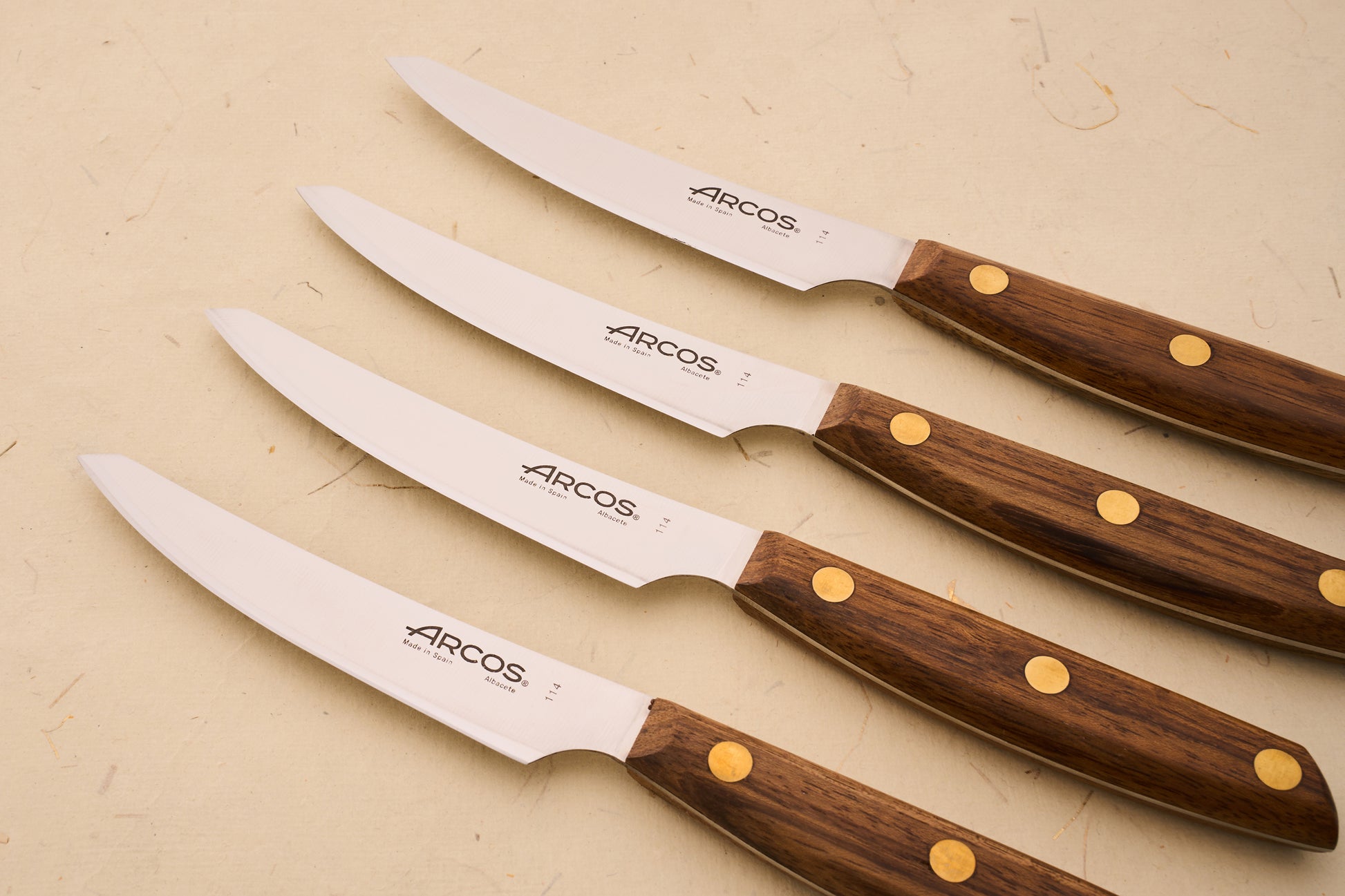 Arcos Nordika 4pc Steak Knife Set, featuring stainless steel blades with wood handles, expertly crafted in Spain, ideal for precise, clean cuts.