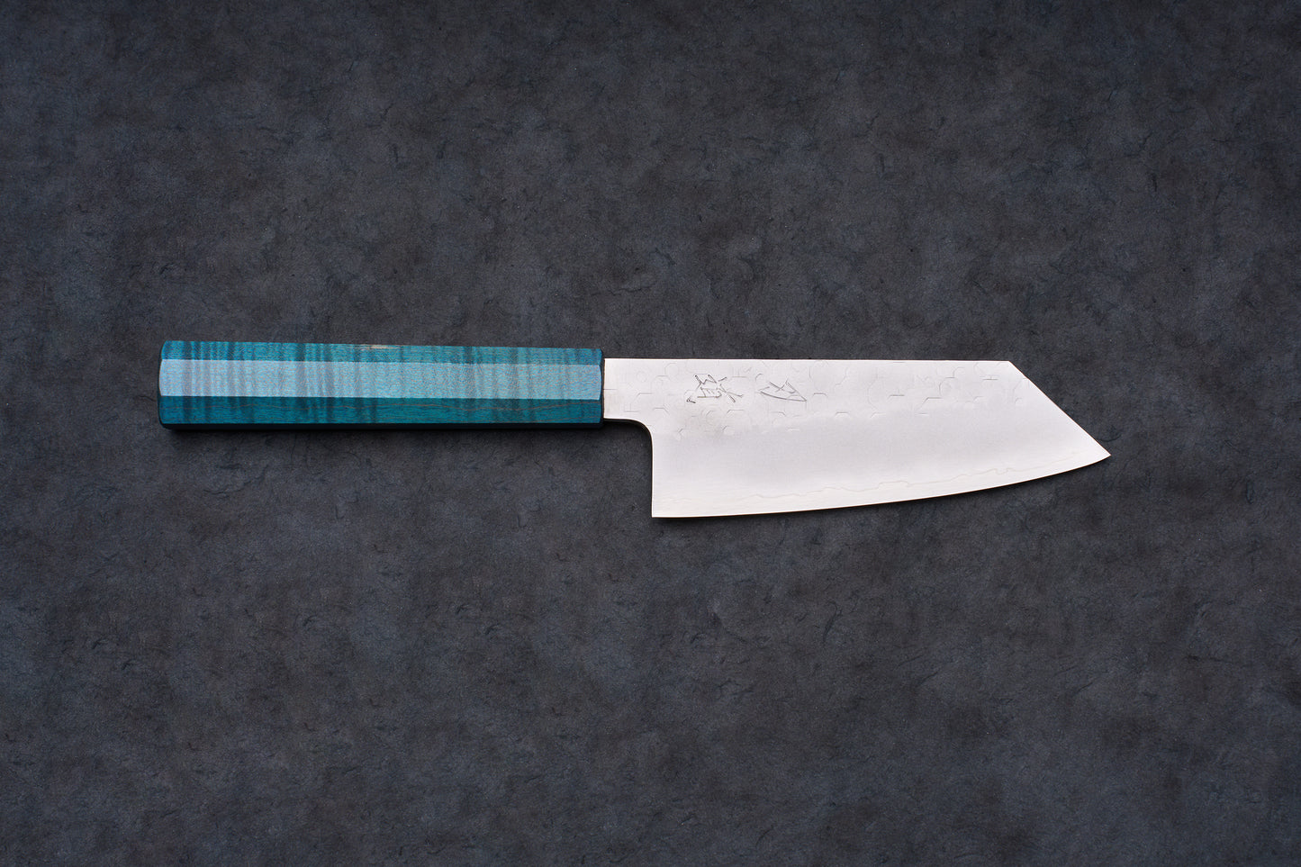 Blue Handle Hado Shiosai Ko-Bunka 135mm knife with a hammered stainless blade and turquoise octagonal handle, displayed on a dark slate surface.