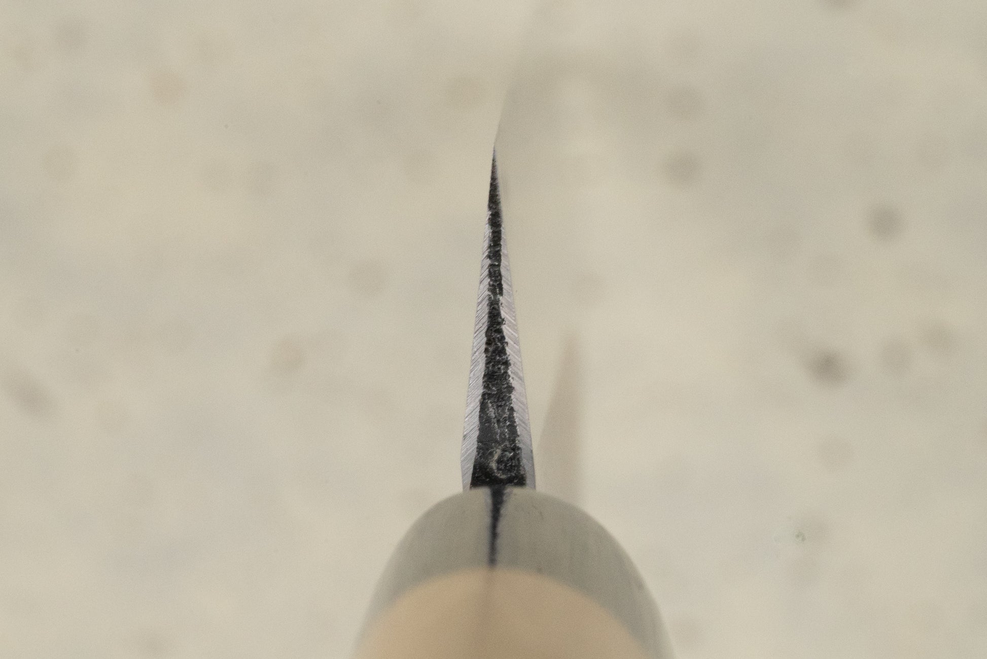 Masamoto KK Shirogami Kasumi Yanagiba 300mm knife, showcasing a finely sharpened steel blade from a head-on view, with a hint of its wooden handle, illustrating its precision craftsmanship.