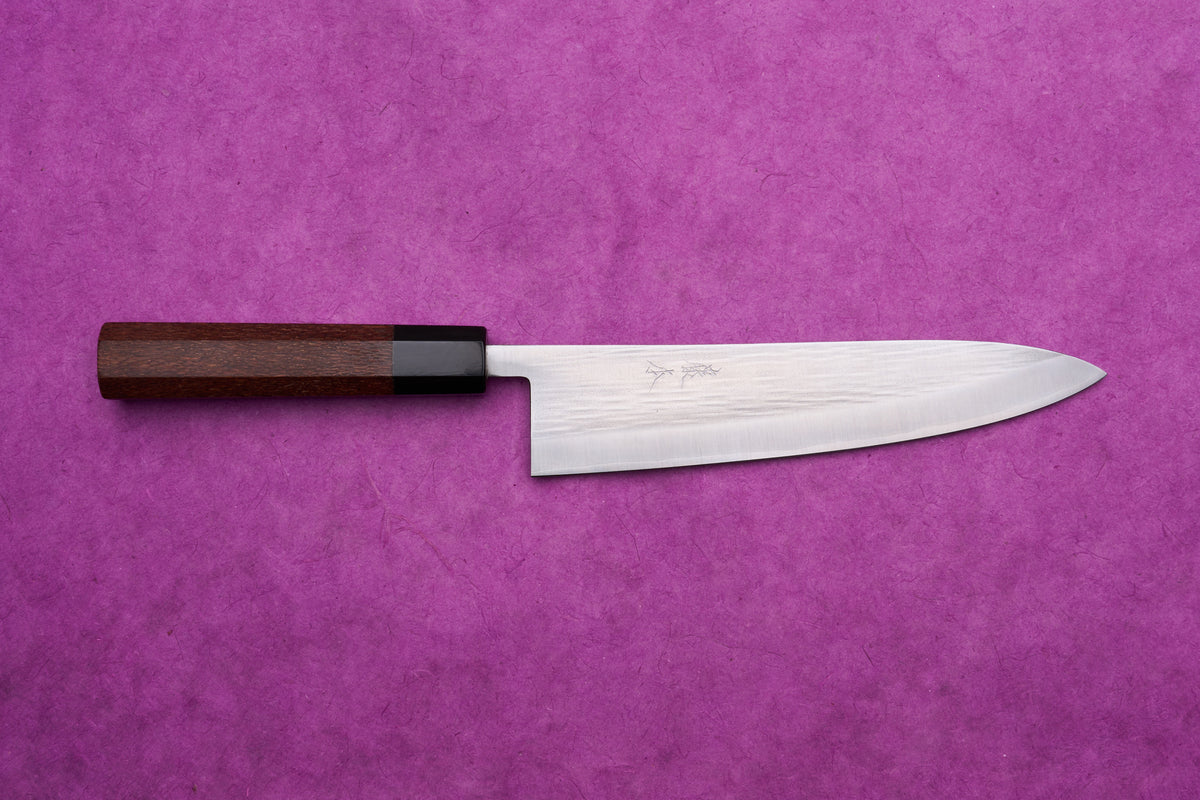 Fujimoto AS Sazanami Gyuto 210mm with a stainless-steel blade and octagonal wooden handle, displayed on a textured purple background.