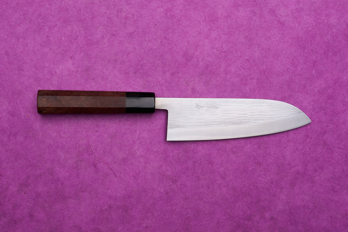 Fujimoto AS Sazanami Santoku 165mm knife with stainless steel blade and dark wood handle, displayed on a purple textured background.
