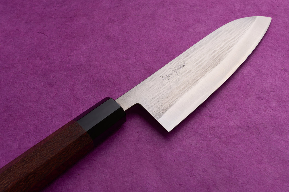 Fujimoto AS Sazanami Santoku 165mm knife with a stainless steel blade, engraved kanji, and octagonal wooden handle, displayed on a purple textured surface.