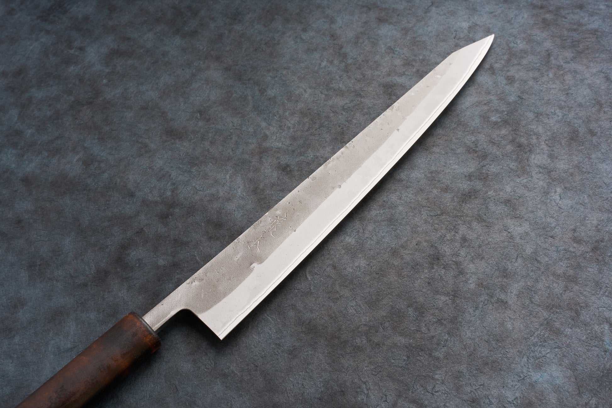 Fujimoto Nashiji Sujihiki 240mm, a high-polish, single-edged slicing knife with a wooden wa handle, expertly crafted for precision in slicing meats, embodying the perfect blend of carbon and stainless steel.