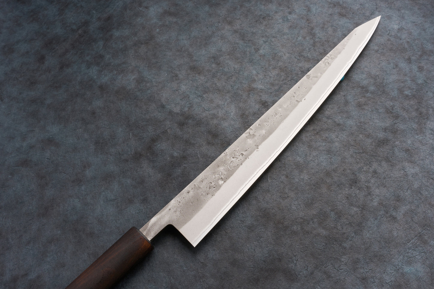 Fujimoto Nashiji Sujihiki 270mm: A sleek, single-edged Japanese slicing knife with a polished steel blade, subtle hammer textures, faint hamon line, and a dark wooden handle, crafted for precision slicing.