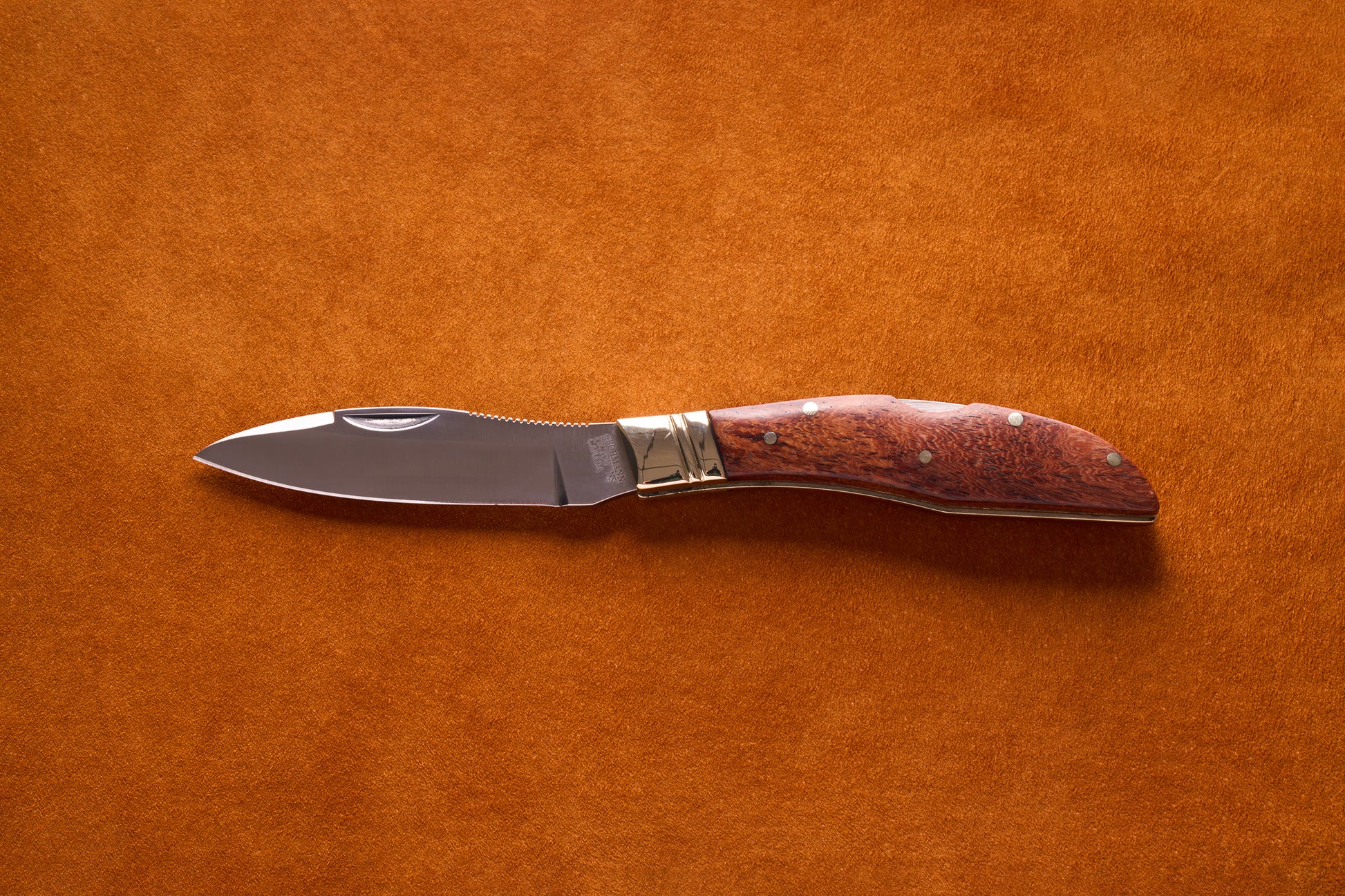 Grohmann Mini Russell Lockblade with Rosewood Handle, 4, featuring a polished stainless-steel blade and jimping, displayed on a suede-like background.