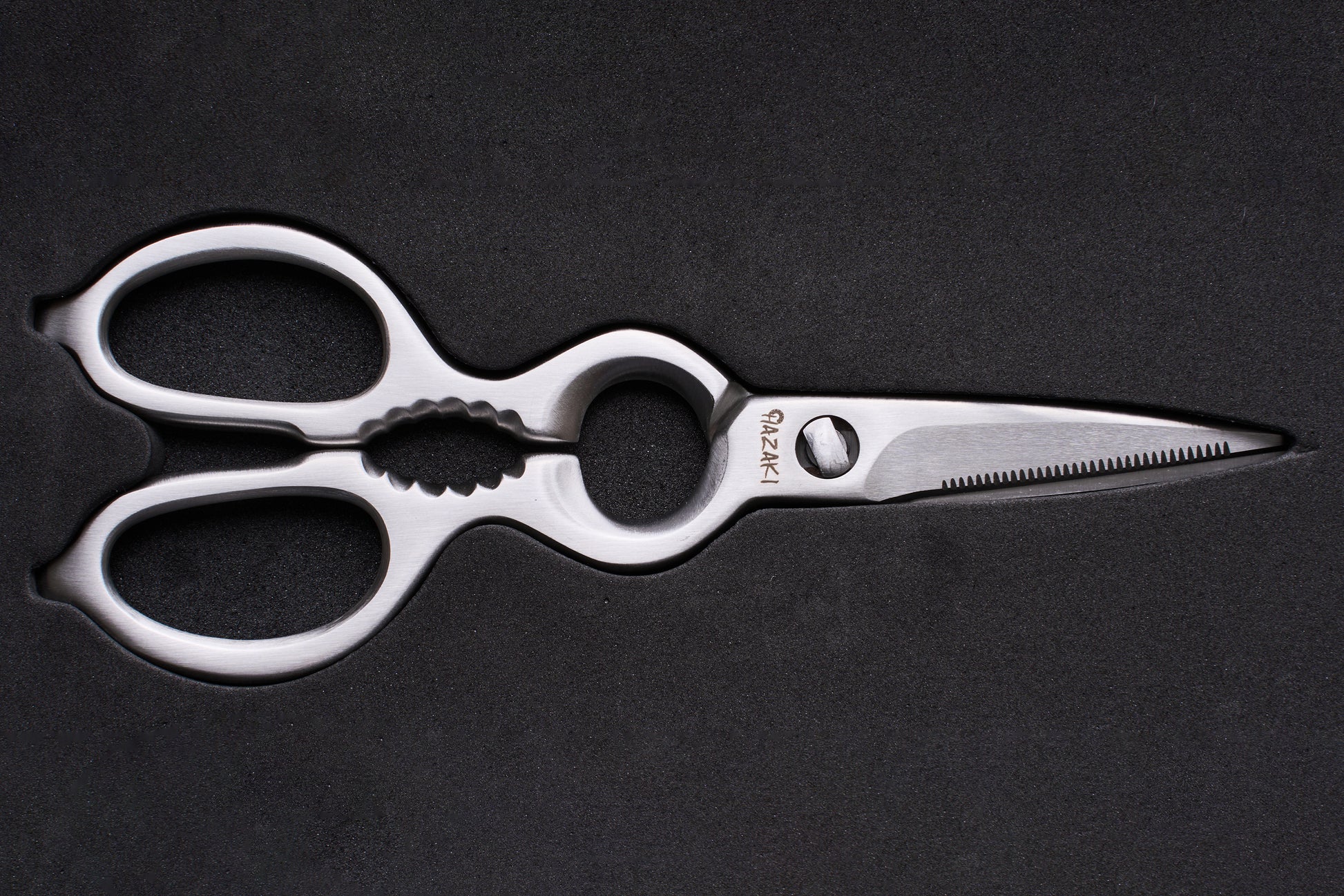 Hazaki Stainless Kitchen Shears, featuring polished stainless steel with ergonomic looped handles, a serrated blade, built-in nutcracker, and bottle opener, ideal for versatile kitchen use.