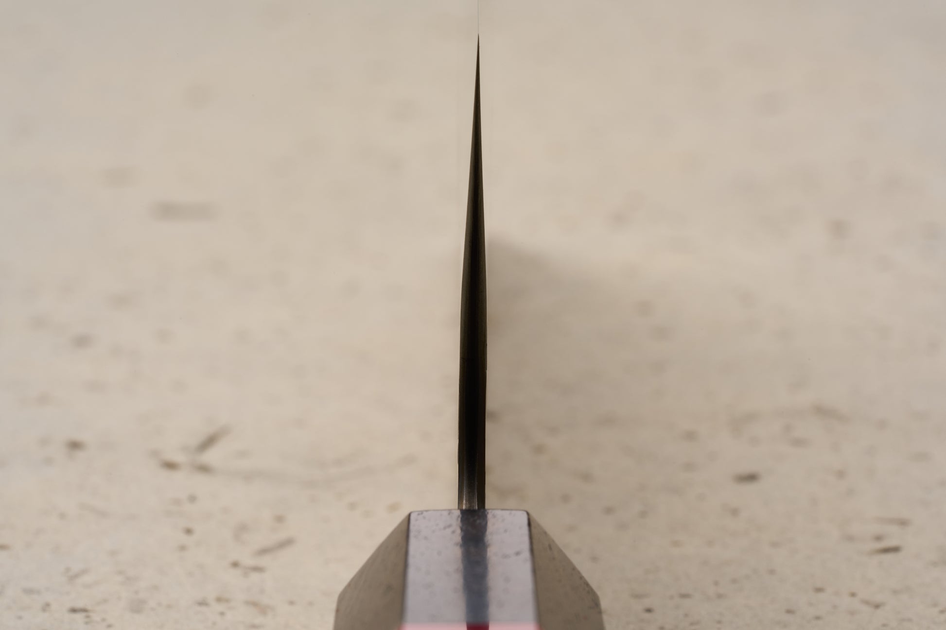 ICHIE x Shibata Knives SG2 Tsuchime Nakiri 165mm stands upright on a dark base, showcasing its thin metal blade's spine, designed for precise vegetable chopping, reflecting Japanese craftsmanship from Knifewear.