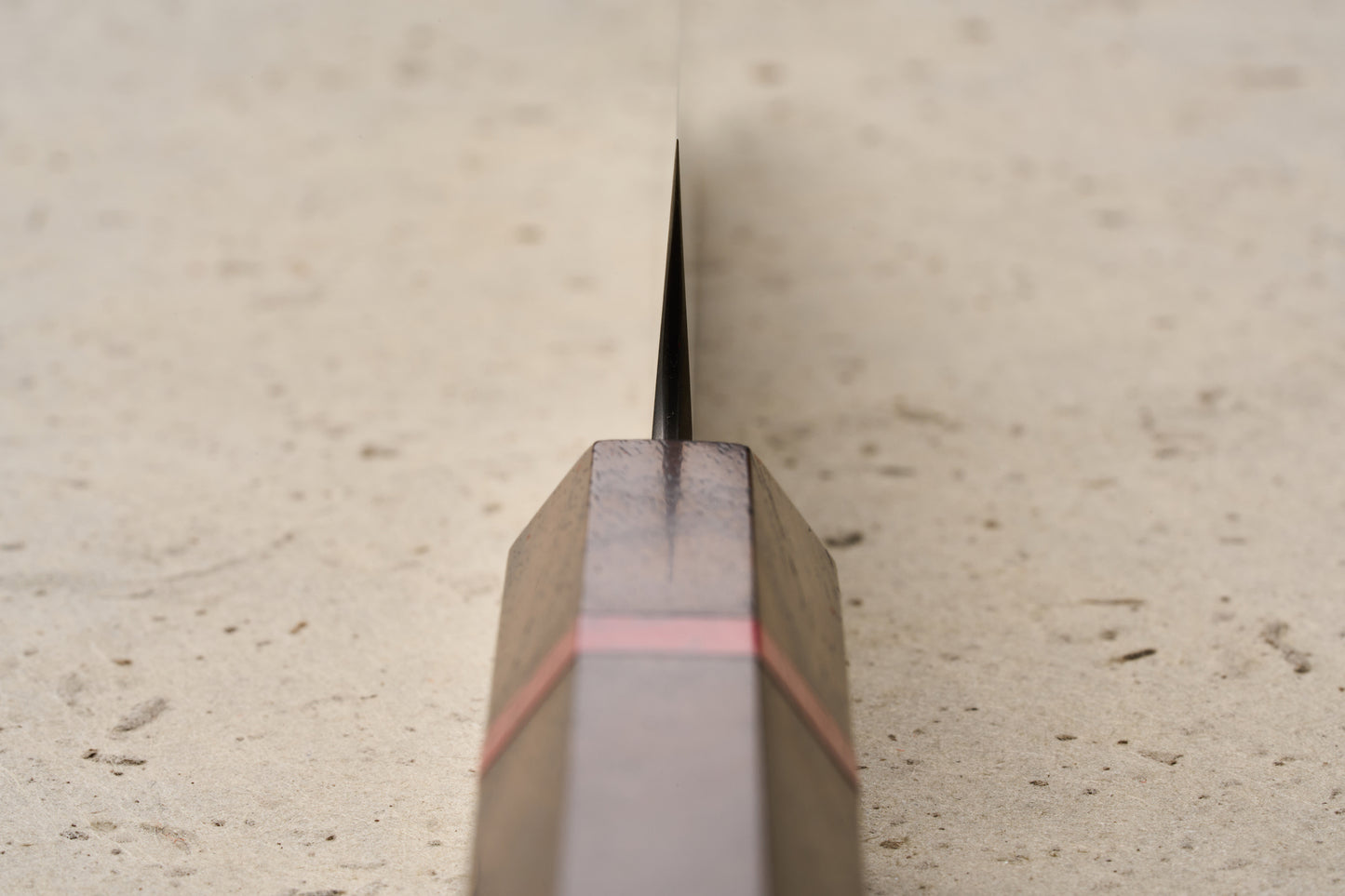 ICHIE x Shibata Knives SG2 Tsuchime Petty 135mm features an octagonal, spalted wood handle with a red accent, captured in a detailed close-up along the blade spine on a stone surface.