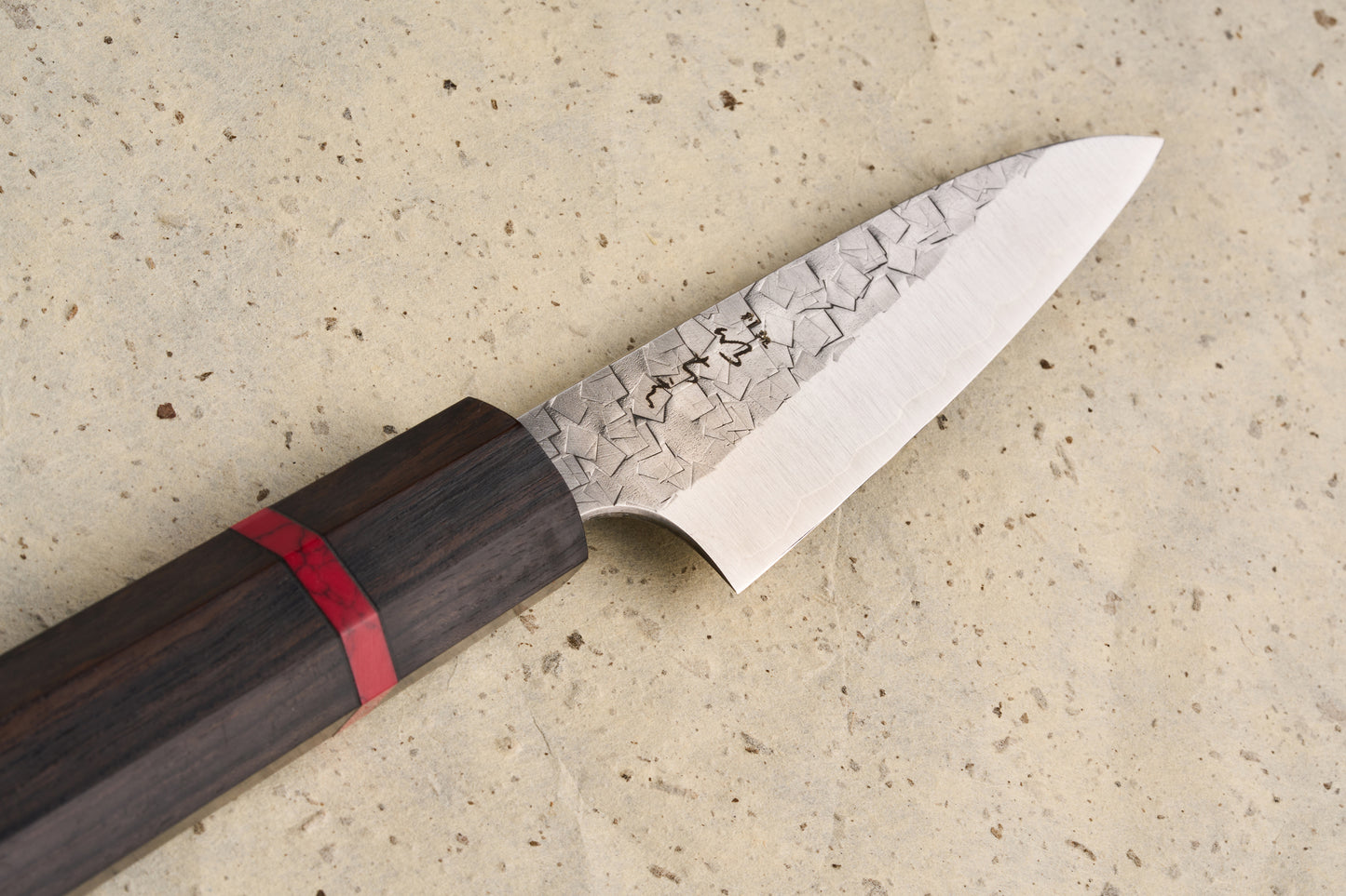 ICHIE x Shibata Knives SG2 Tsuchime Petty 90mm, showcasing a hammered blade with kanji etchings, complemented by a dark wooden wa-handle with red accent, ideal for precise kitchen tasks.