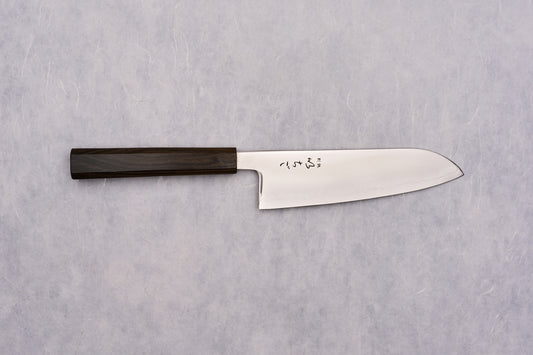 ICHIGO SLD Migaki Santoku 170mm lies flat, showcasing its polished steel blade with Japanese characters and dark wooden handle, embodying timeless craftsmanship and precision, ideal for versatile kitchen tasks.