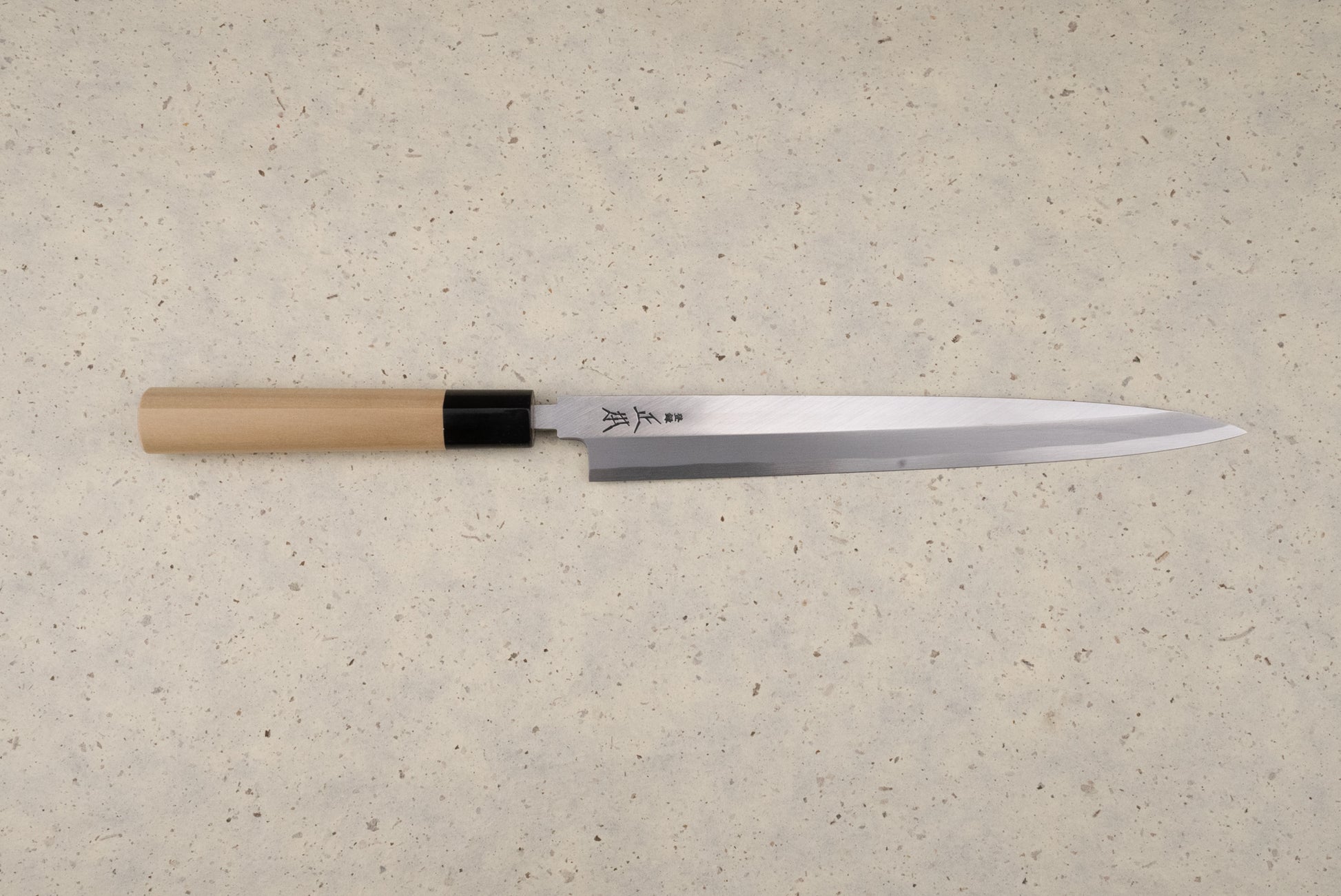Masamoto KK Shirogami Kasumi Yanagiba 240mm knife with a polished single-bevel steel blade and etched Japanese characters, featuring an octagonal wooden handle, perfect for precise sashimi slicing.