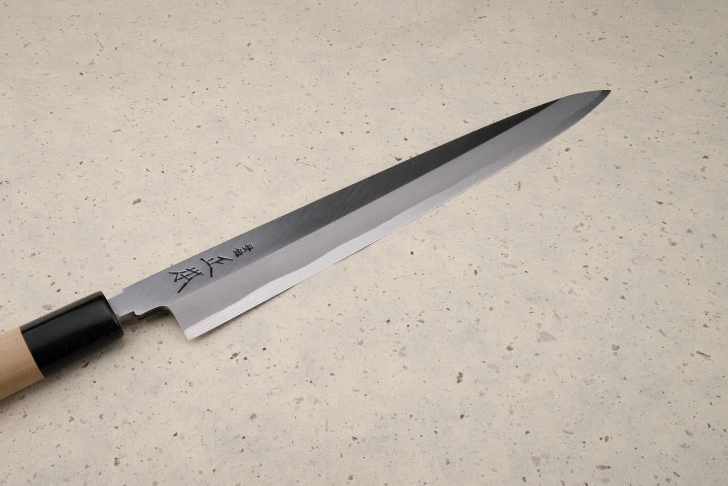 Masamoto KK Shirogami Kasumi Yanagiba 270mm, a slender Japanese slicing knife with a polished single-bevel blade etched with characters, and a simple wooden handle, ideal for precision slicing.
