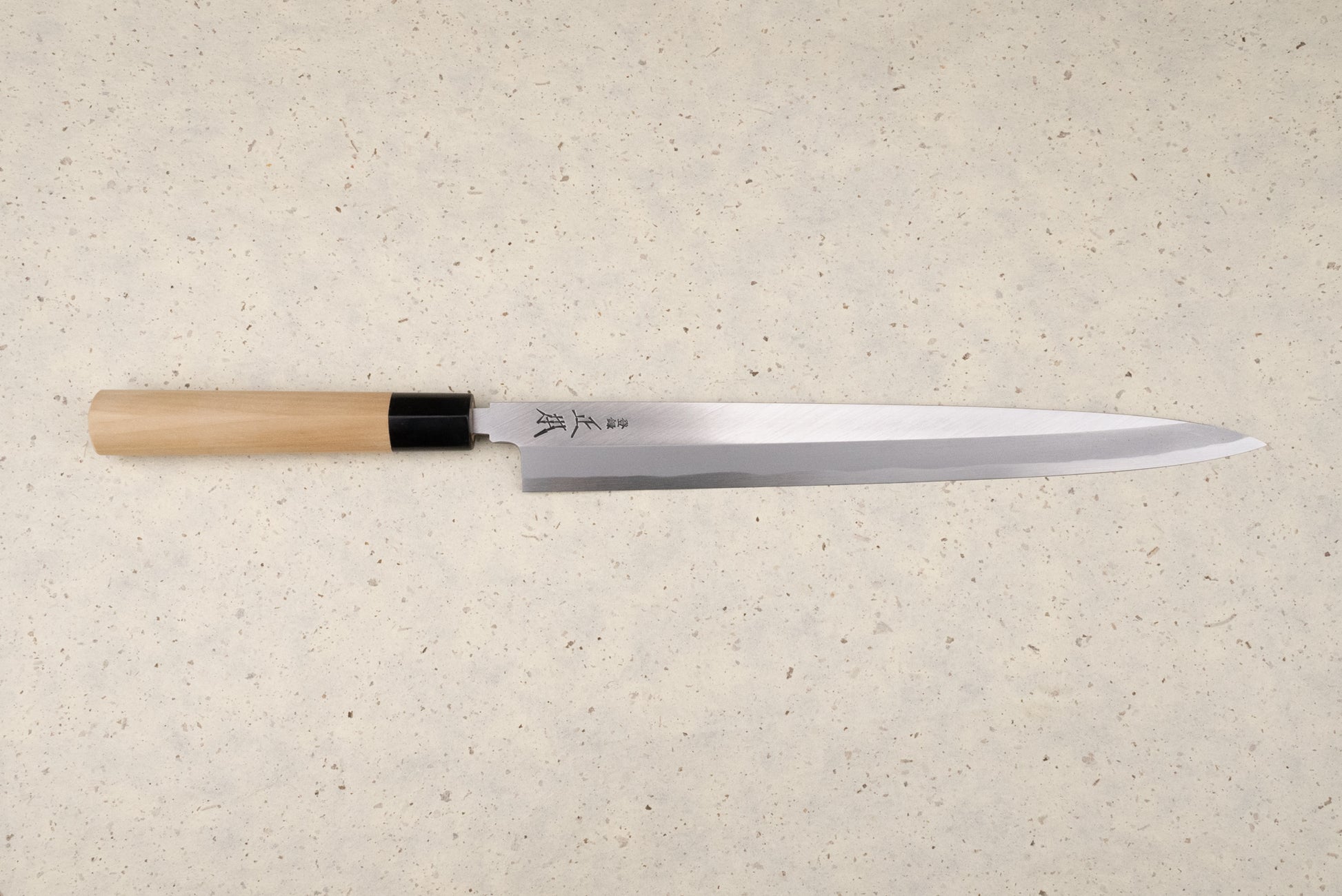 Masamoto KK Shirogami Kasumi Yanagiba 300mm knife with a single-bevel blade and Japanese characters, featuring an octagonal wooden handle with a black ferrule, perfect for slicing sashimi elegantly.