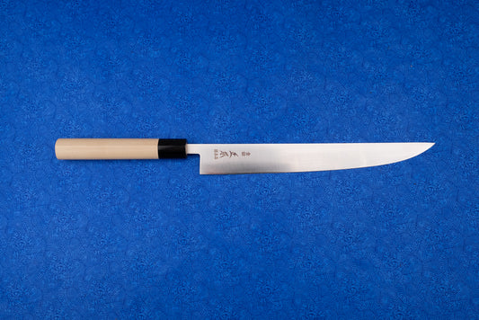 Masamoto MV Tachigata Sujihiki 255mm, a Japanese-style slicing knife, features a single-bevel stainless steel blade with kanji and a natural wood handle, displayed on a vibrant blue patterned cloth.