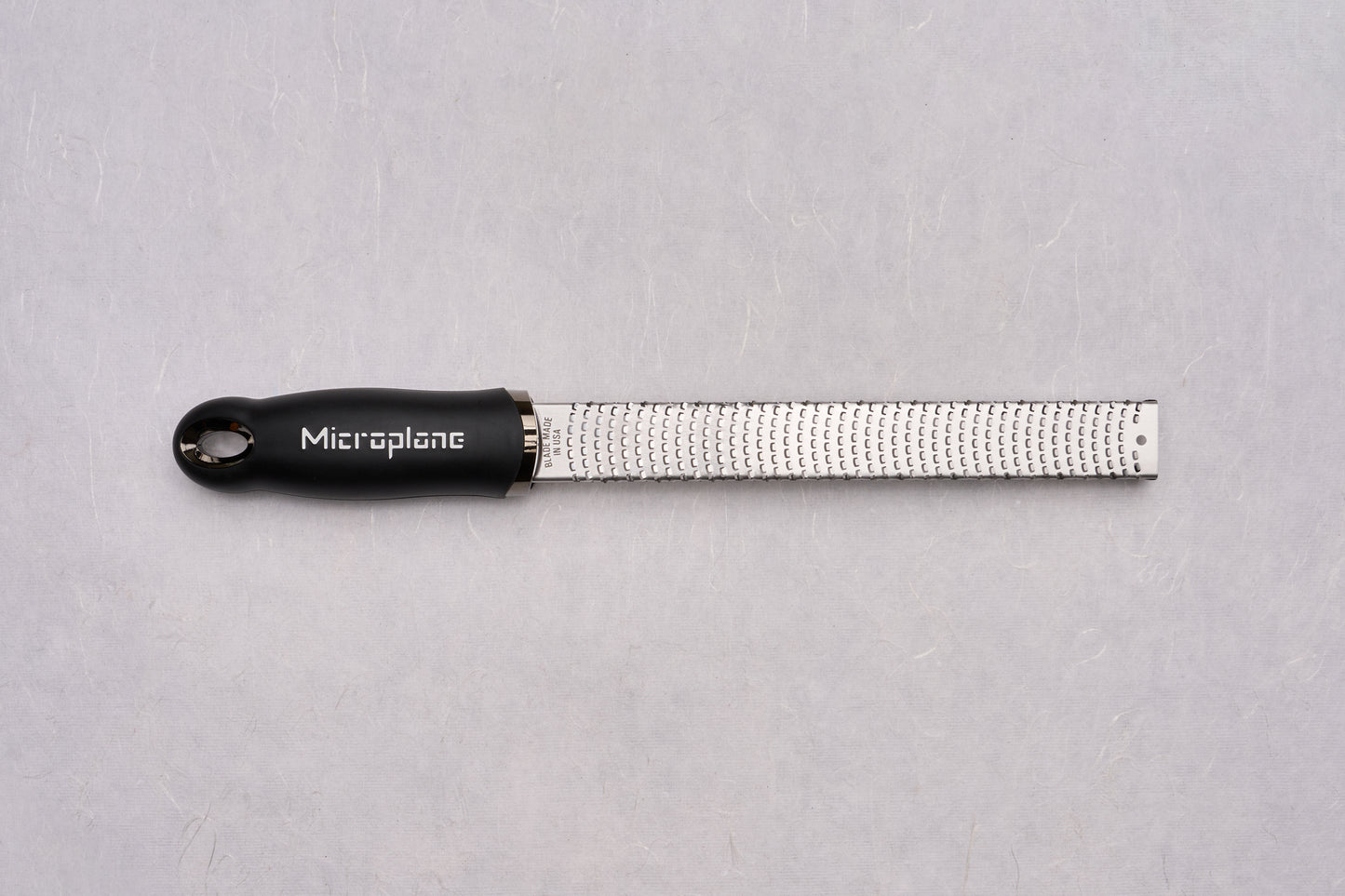 Microplane Premium Classic Zester with a slender stainless-steel surface and black ergonomic handle, ideal for finely grating zest and spices, perfect for chefs valuing precision and quality.