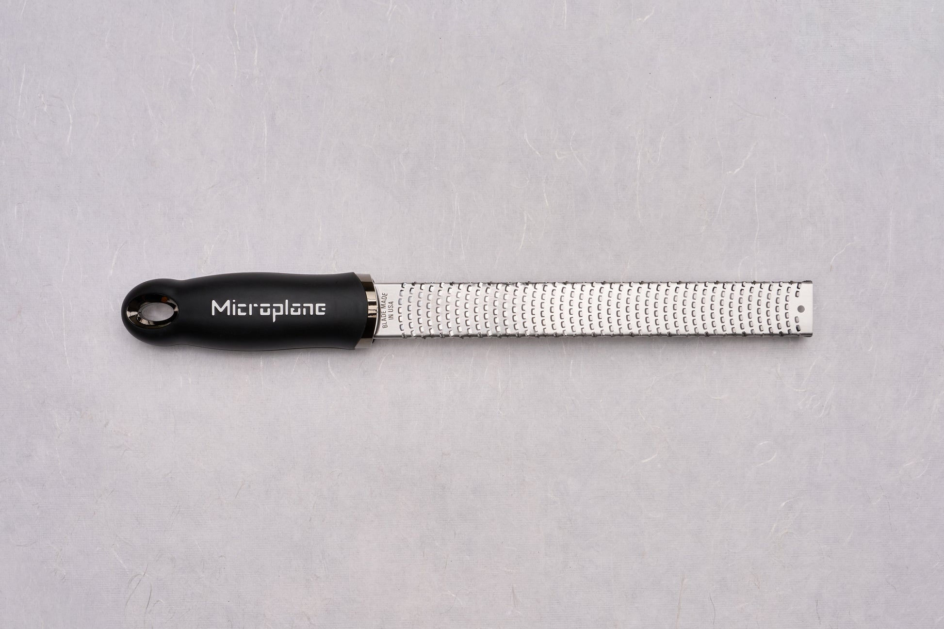 Microplane Premium Classic Zester with a slender stainless-steel surface and black ergonomic handle, ideal for finely grating zest and spices, perfect for chefs valuing precision and quality.