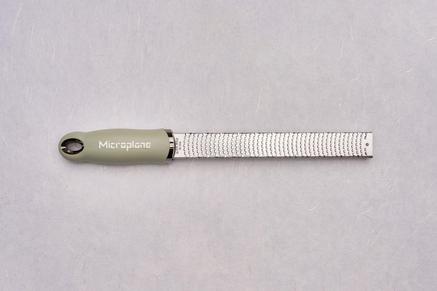Microplane Premium Classic Zester, featuring a sleek stainless-steel blade and an ergonomic olive-green handle, ideal for zesting citrus or grating hard cheeses, a must-have tool for culinary precision.