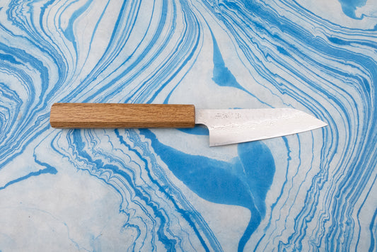 Nigara SPG STRIX Tsuchime Damascus Petty 120mm knife with a straight wooden handle and a Damascus-pattern steel blade, displayed on a blue-and-white marbled surface, ideal for precise kitchen tasks.
