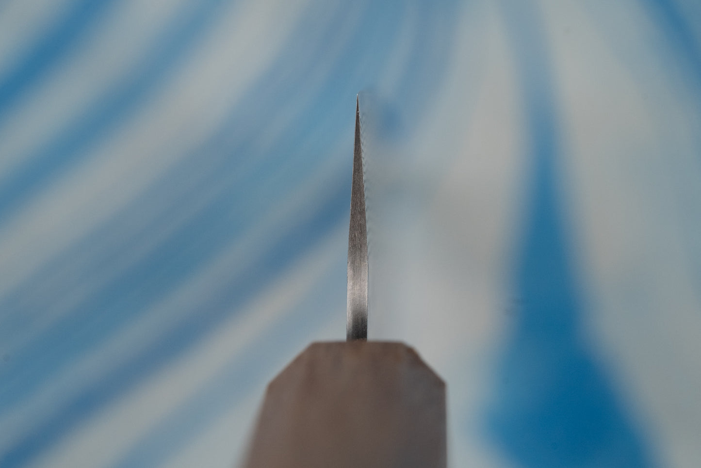 Nigara SPG STRIX Tsuchime Damascus Petty 150mm knife, featuring a slender steel blade tip and spine, emerges from its handle, ideal for precise cutting tasks on a board.