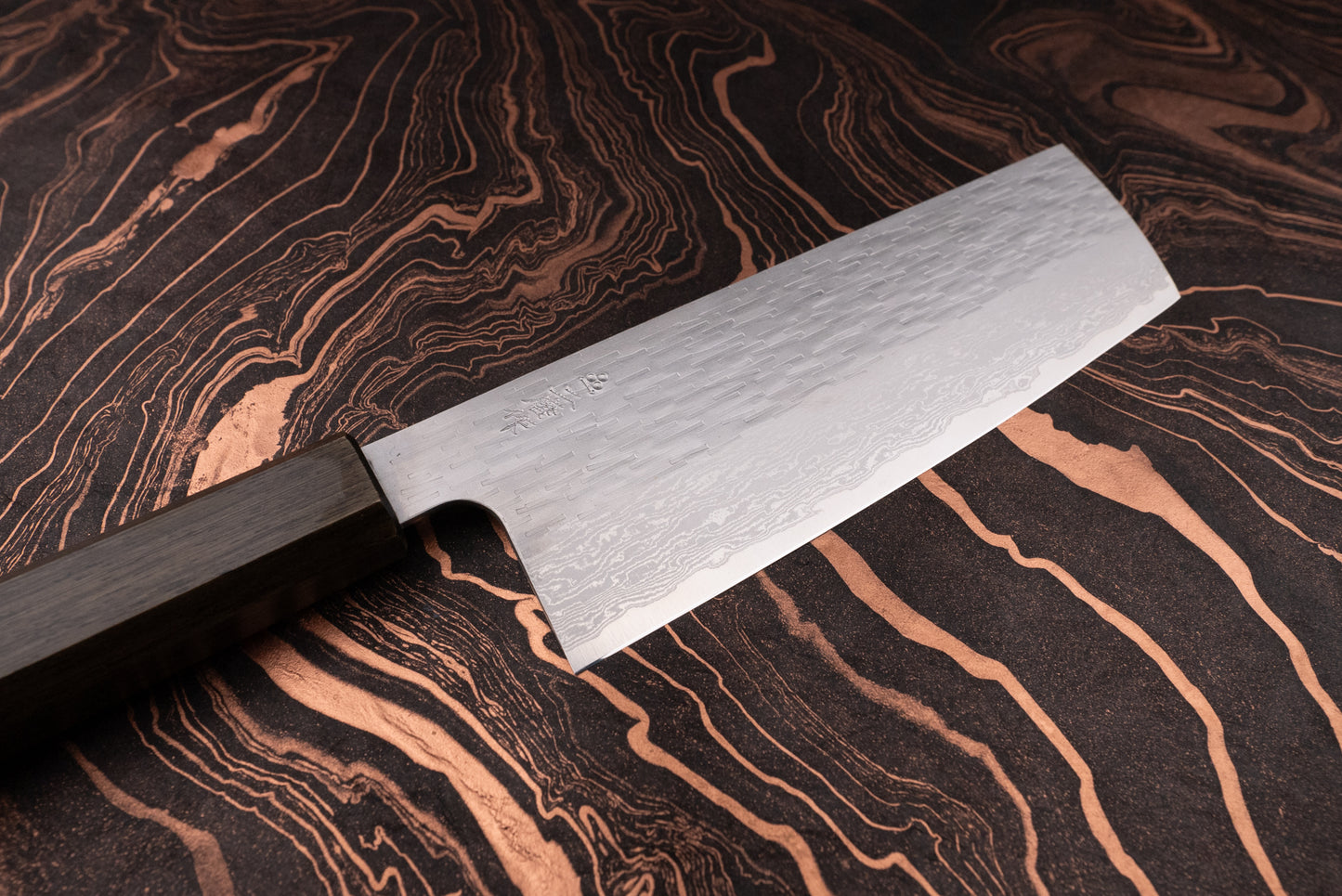 Nigara VG XEOS Tsuchime Damascus Nakiri 180mm features a wide, rectangular damascus-pattern steel blade with a hammered finish and an octagonal dark wooden handle, perfect for precise vegetable chopping.