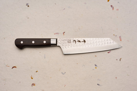 Sakai Takayuki SG2 Tsuchime Damascus Western Kengata Gyuto 190mm features a hammered, Damascus-patterned steel blade with Japanese characters and a dark wooden handle, embodying expert craftsmanship ideal for culinary enthusiasts.