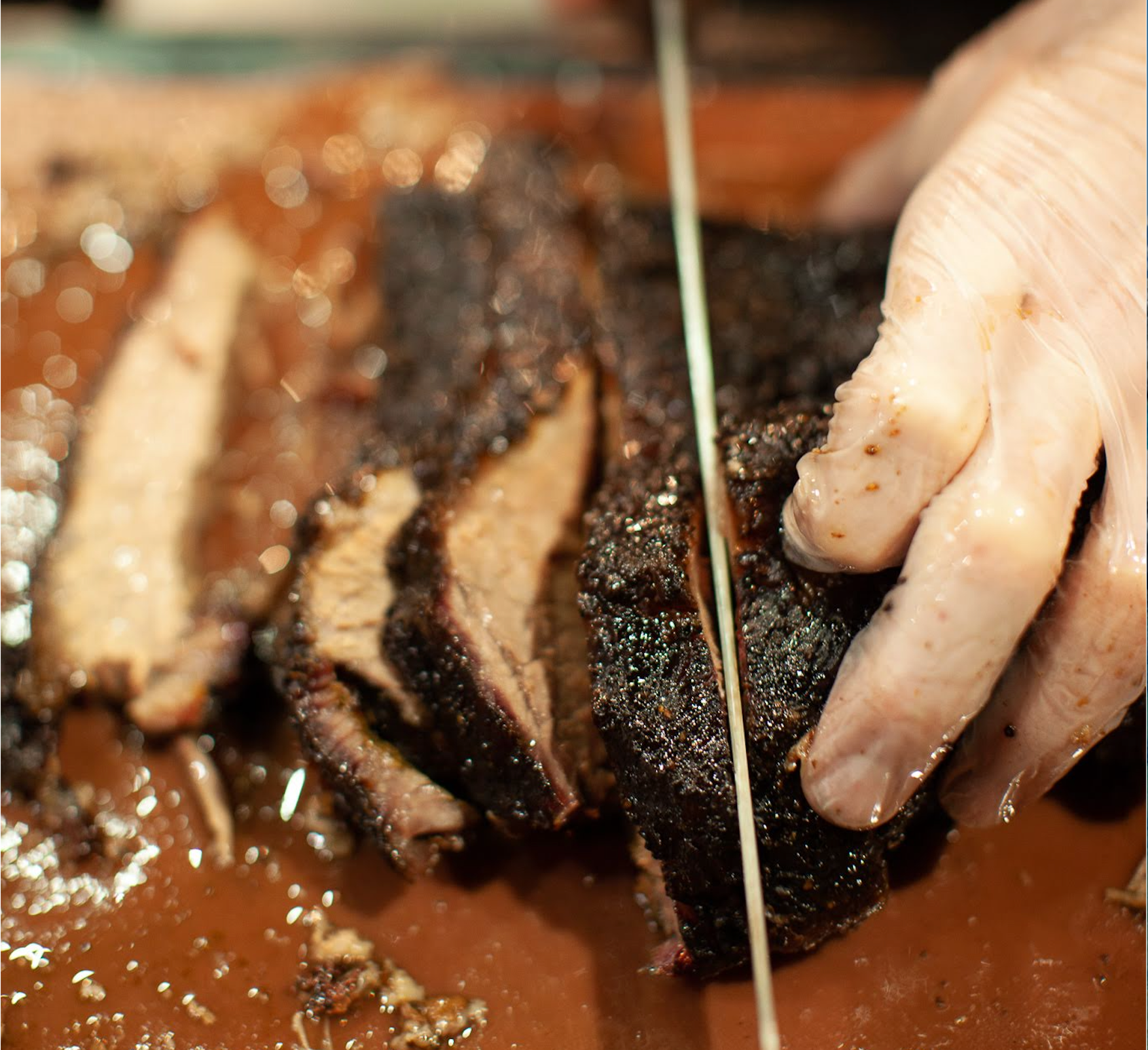 Close-up of a smoked beef brisket being sliced during the Prairie Dog Brewing X Knifewear Brisket Smoking Class in Calgary, showcasing its peppery crust, pink smoke ring, and juicy interior.
