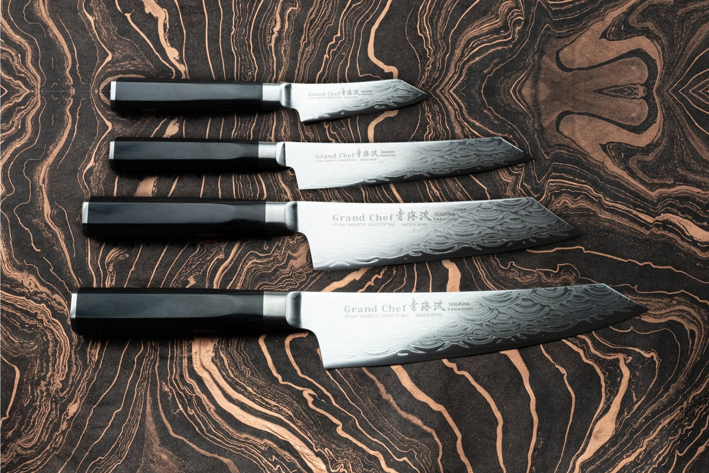 Sakai Takayuki Grand Chef Seigaiha 4 Piece Knife Set features Damascus-pattern blades with dark handles, expertly crafted for precision and sharpness, ideal for both home cooks and professional chefs.