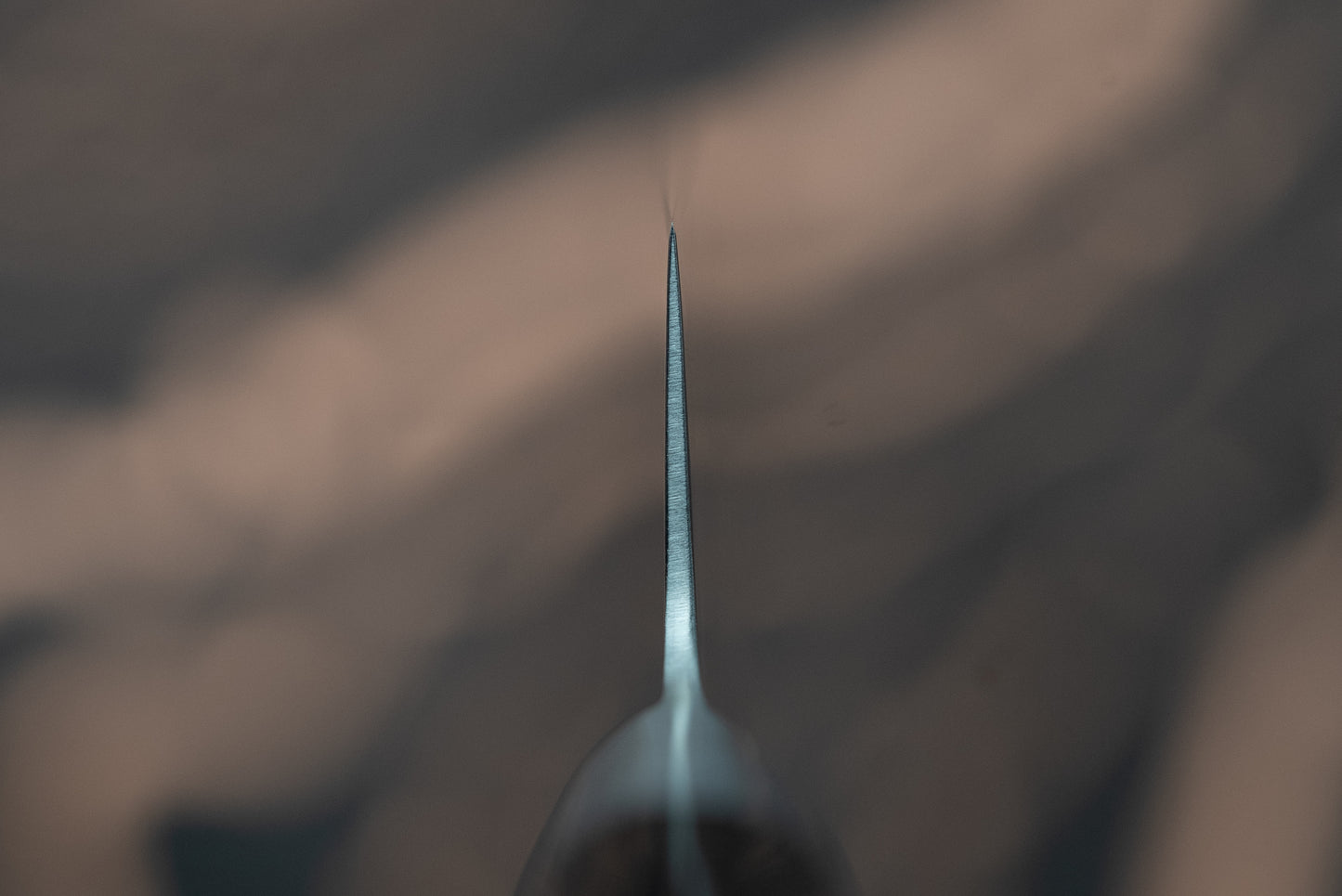 The Sakai Takayuki Grand Chef Seigaiha Kengata Petty 150mm showcases its super thin, sharp blade, viewed tip-first, highlighting the precision craftsmanship of this essential kitchen tool.