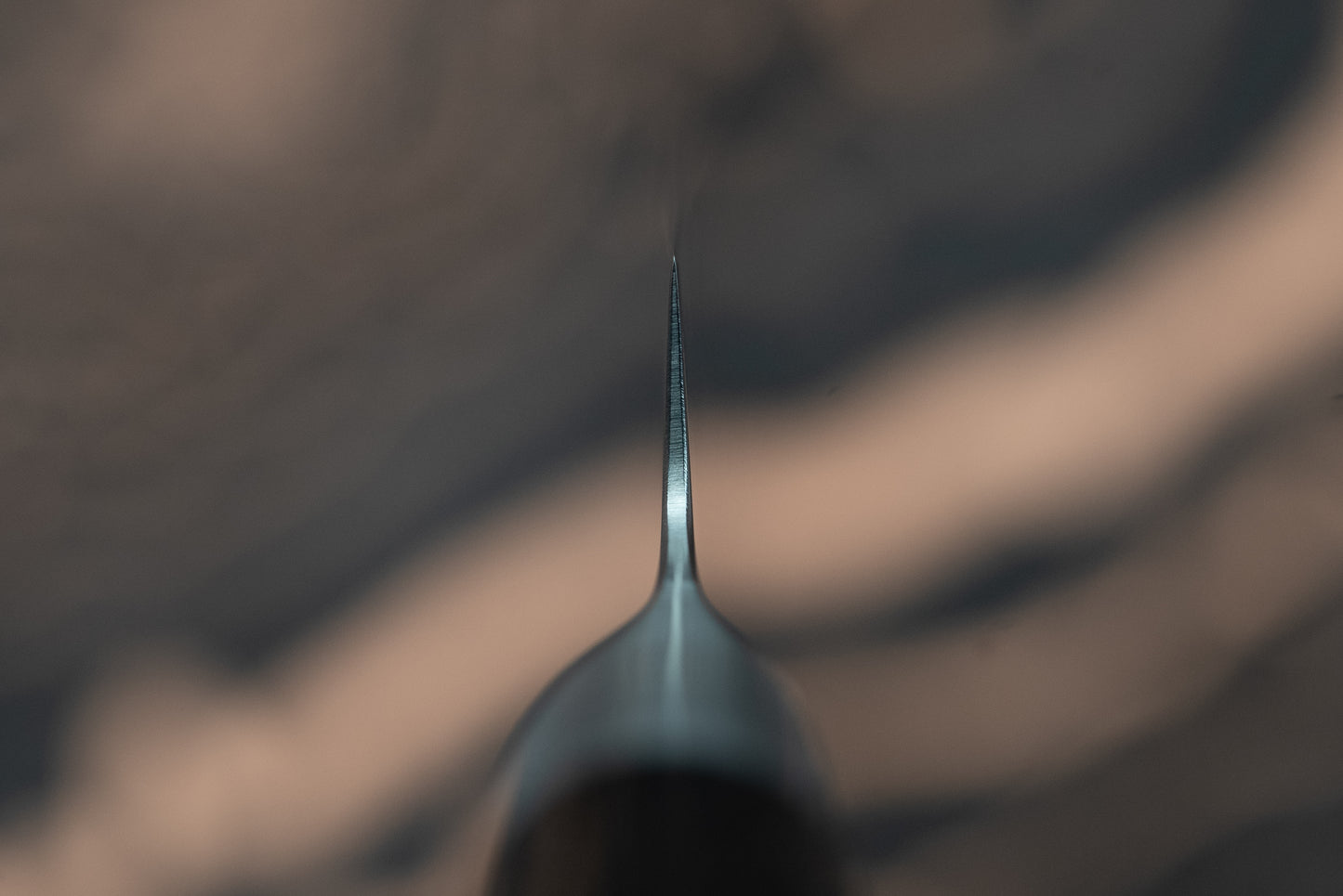 Close-up of Sakai Takayuki Grand Chef Seigaiha Kengata Petty 80mm knife, showcasing its sharp tip and slender steel blade with blurred handle, ideal for precise cutting tasks.