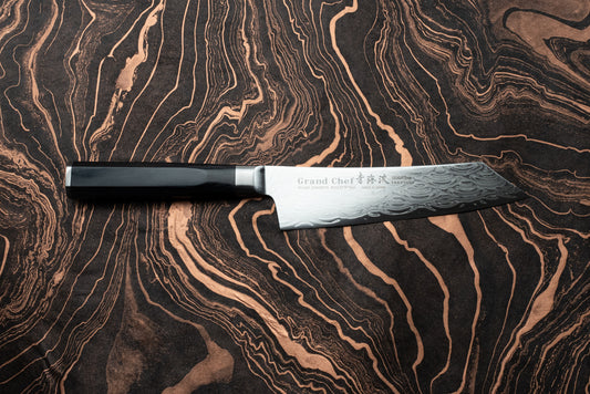 Sakai Takayuki Grand Chef Seigaiha Kengata Santoku 160mm knife, featuring a 45-layer Damascus-pattern blade and polished black handle, displayed on a marbled wood surface, embodying Japanese craftsmanship and precision.