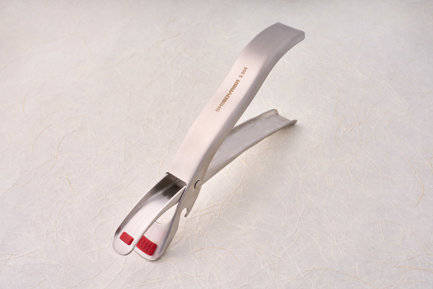Shimoyama Stainless Steel Bowl Clip with red silicone grip pads, ideal for serving or grilling, reflecting Knifewear's dedication to quality chef tools.
