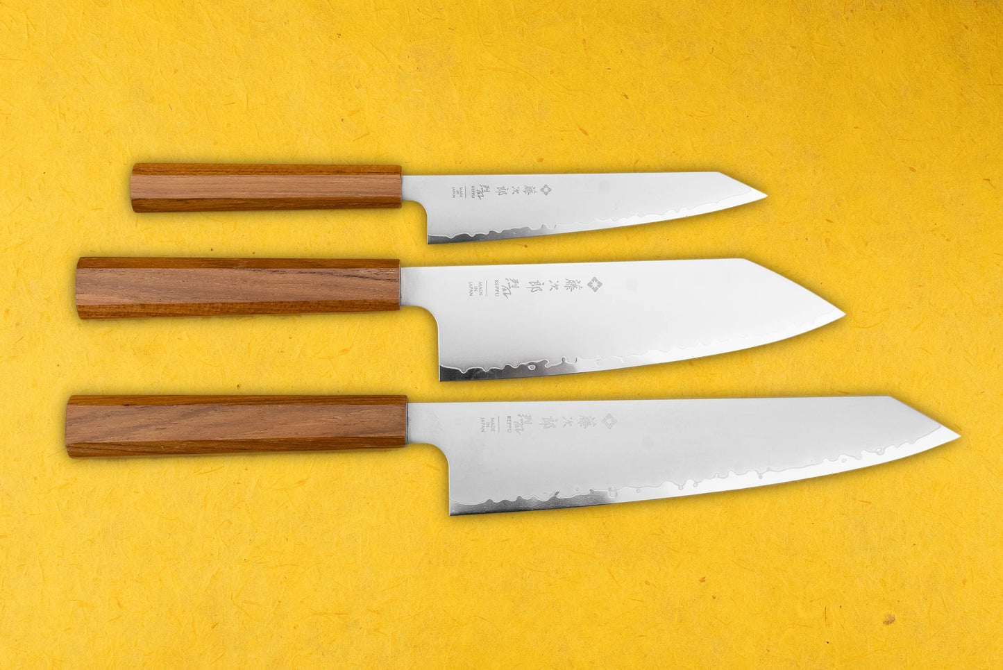 TOJIRO Reppu 3 Piece Knife Set on display, featuring octagonal wooden handles and polished stainless-steel blades with Japanese characters and hammered texture, showcasing sizes from paring to chef’s knife.