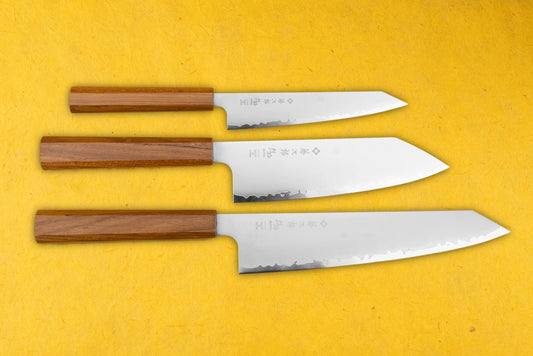 TOJIRO Reppu 3 Piece Knife Set on display, featuring octagonal wooden handles and polished stainless-steel blades with Japanese characters and hammered texture, showcasing sizes from paring to chef’s knife.