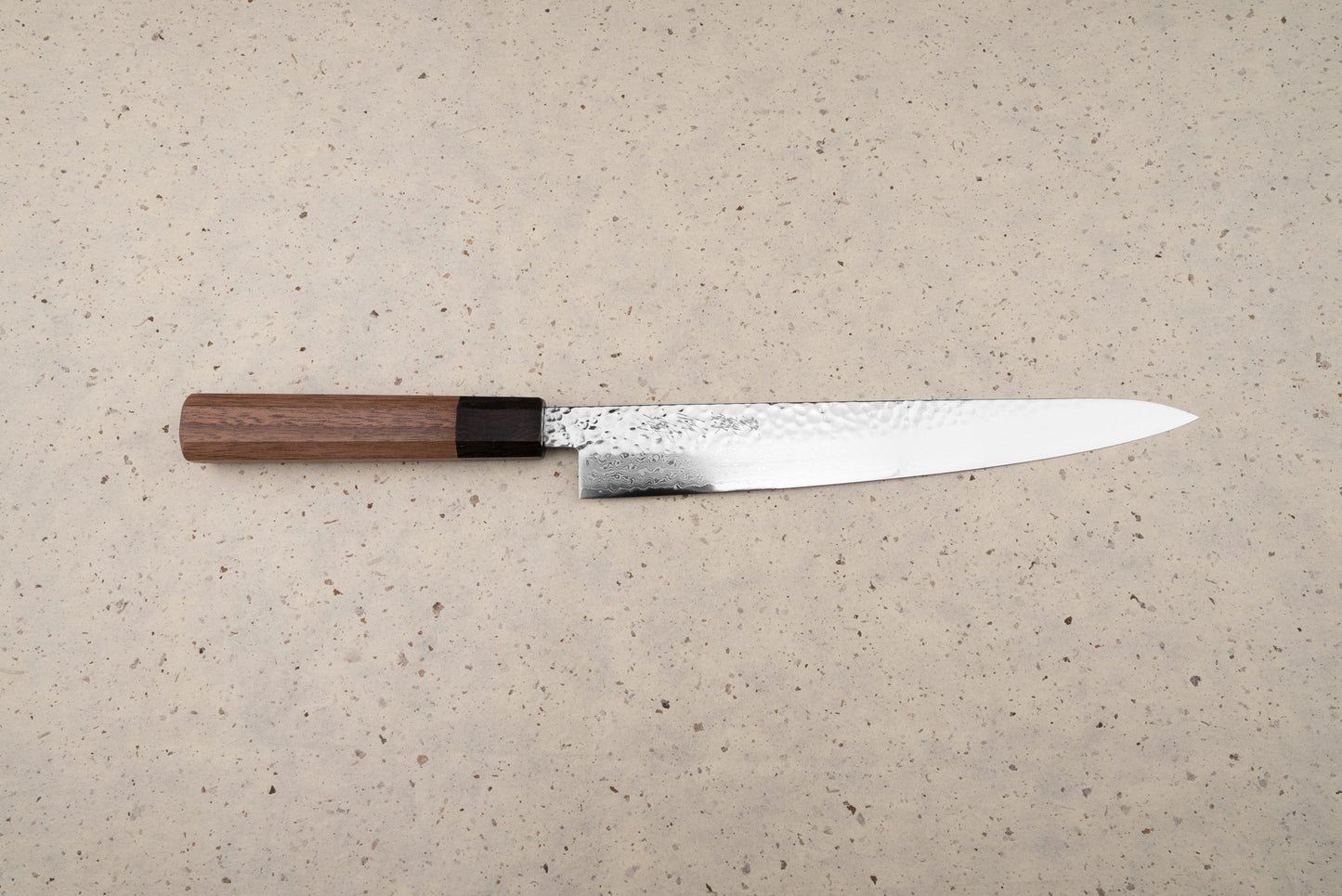Touroku Sakai Yukage Sujihiki 240mm, a Japanese slicing knife featuring a hammer-textured spine, Damascus-style polished edge, and octagonal wooden handle, ideal for precise protein slicing and inspired culinary endeavors.