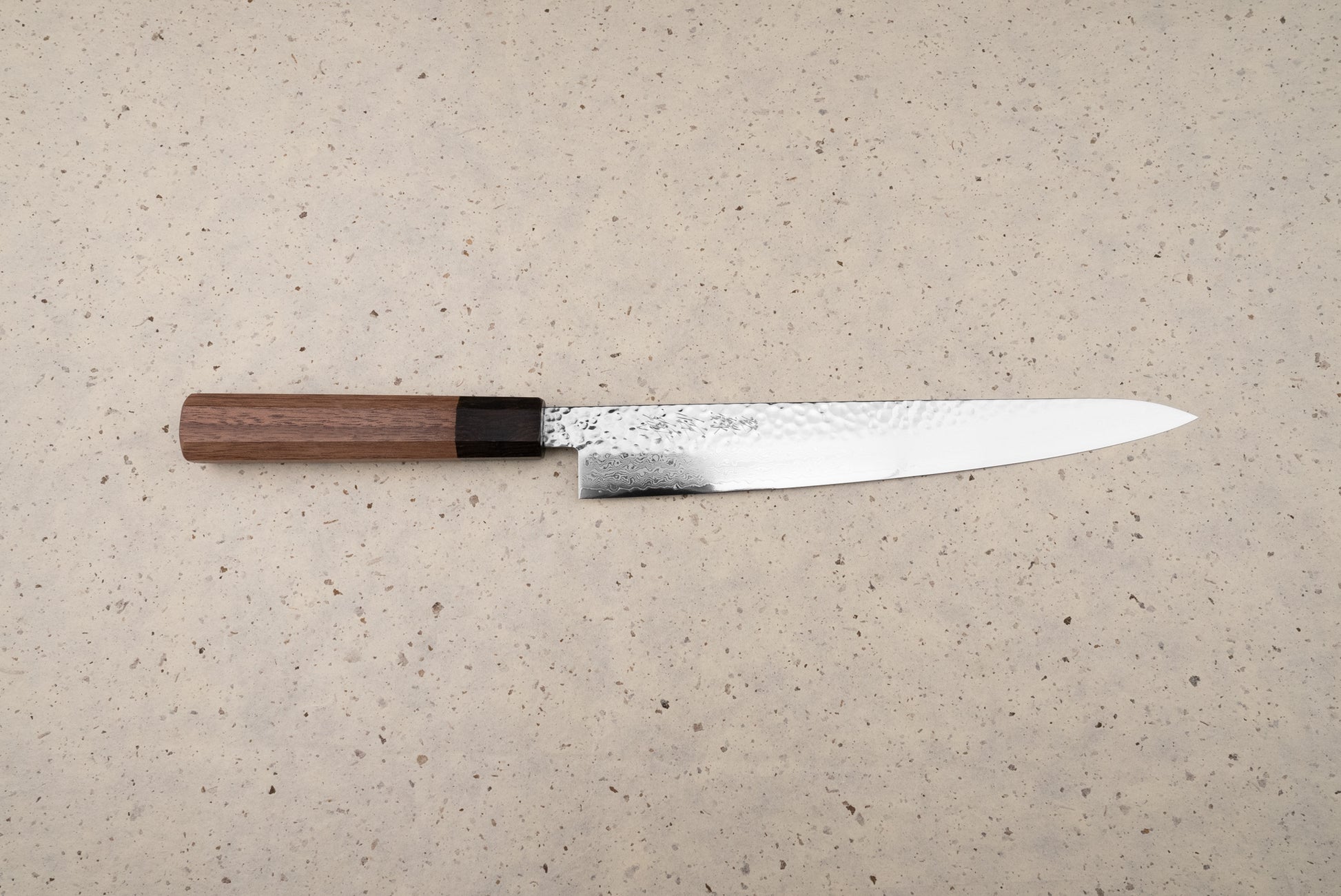 Touroku Sakai Yukage Sujihiki 240mm, a Japanese slicing knife featuring a hammer-textured spine, Damascus-style polished edge, and octagonal wooden handle, ideal for precise protein slicing and inspired culinary endeavors.