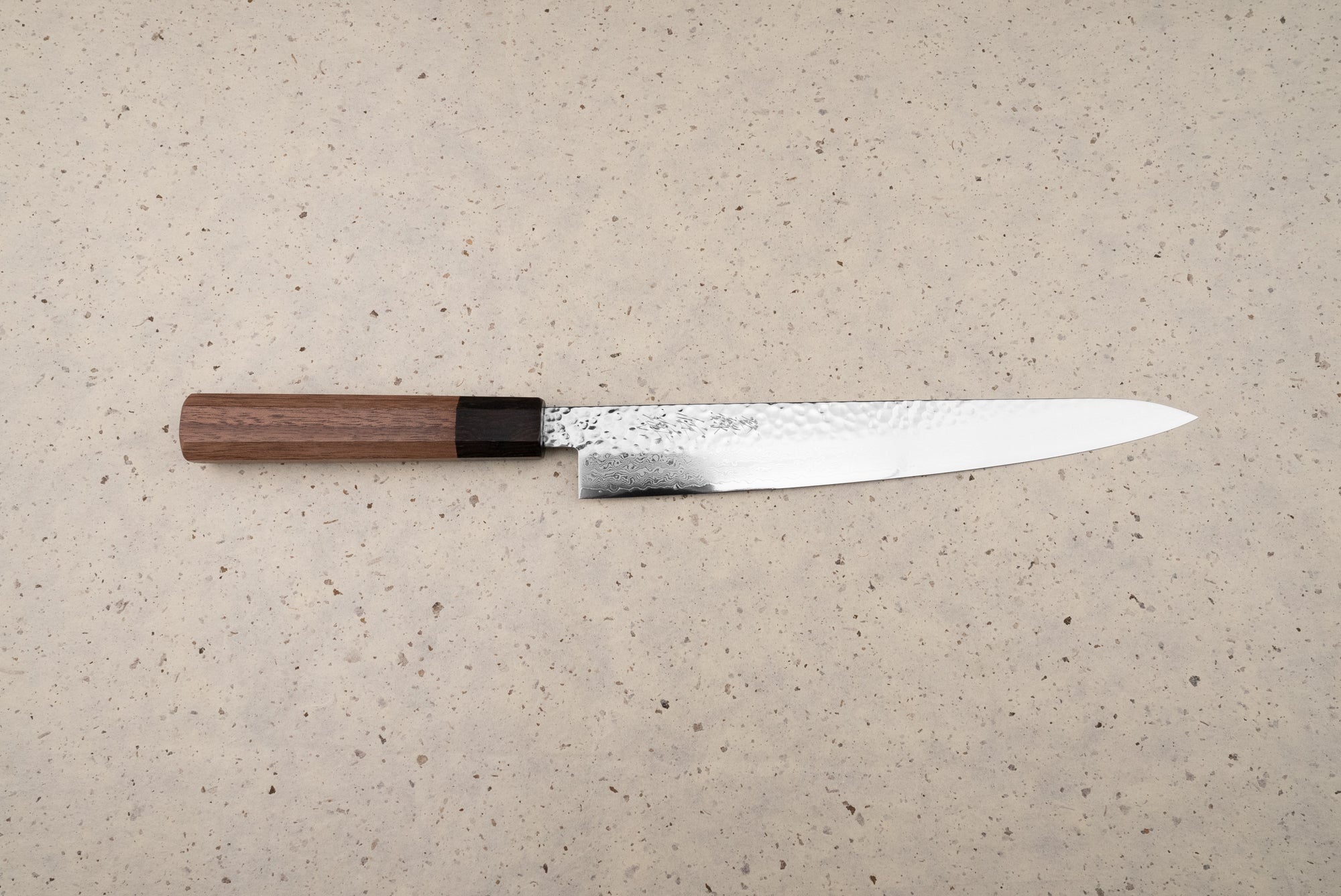 Touroku Sakai Yukage Sujihiki 240mm, a Japanese slicing knife featuring a hammer-textured spine, Damascus-style polished edge, and octagonal wooden handle, ideal for precise protein slicing and inspired culinary endeavors.