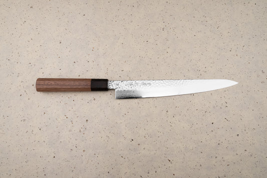 Touroku Sakai Yukage Sujihiki 240mm, a Japanese slicing knife featuring a hammer-textured spine, Damascus-style polished edge, and octagonal wooden handle, ideal for precise protein slicing and inspired culinary endeavors.