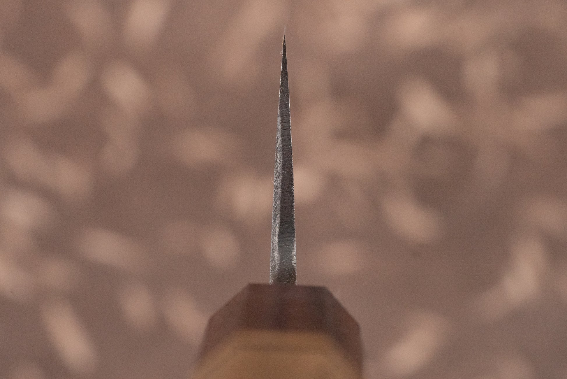 Close-up of the Touroku Sakai Aogami Damascus Kiritsuke Gyuto 210mm's tip, highlighting its precise bevelled edge and wood-handled ferrule, epitomizing expert Japanese craftsmanship and multi-purpose utility in the kitchen.