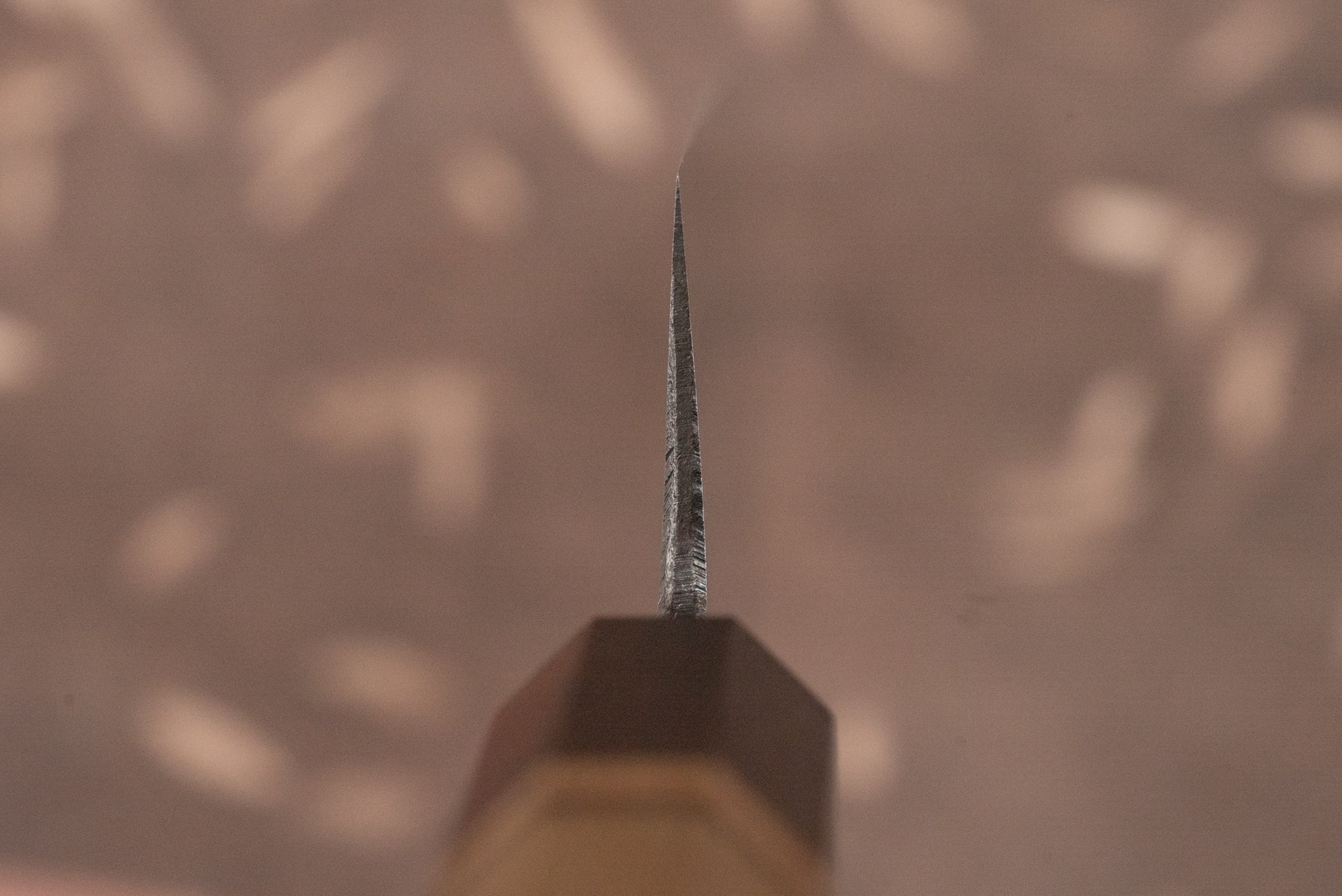 Close-up of Touroku Sakai Aogami Damascus Kiritsuke Petty 150mm knife blade, showcasing its sharp edge and tip, with handle faintly visible, reflecting exceptional Japanese craftsmanship ideal for precise cutting tasks.