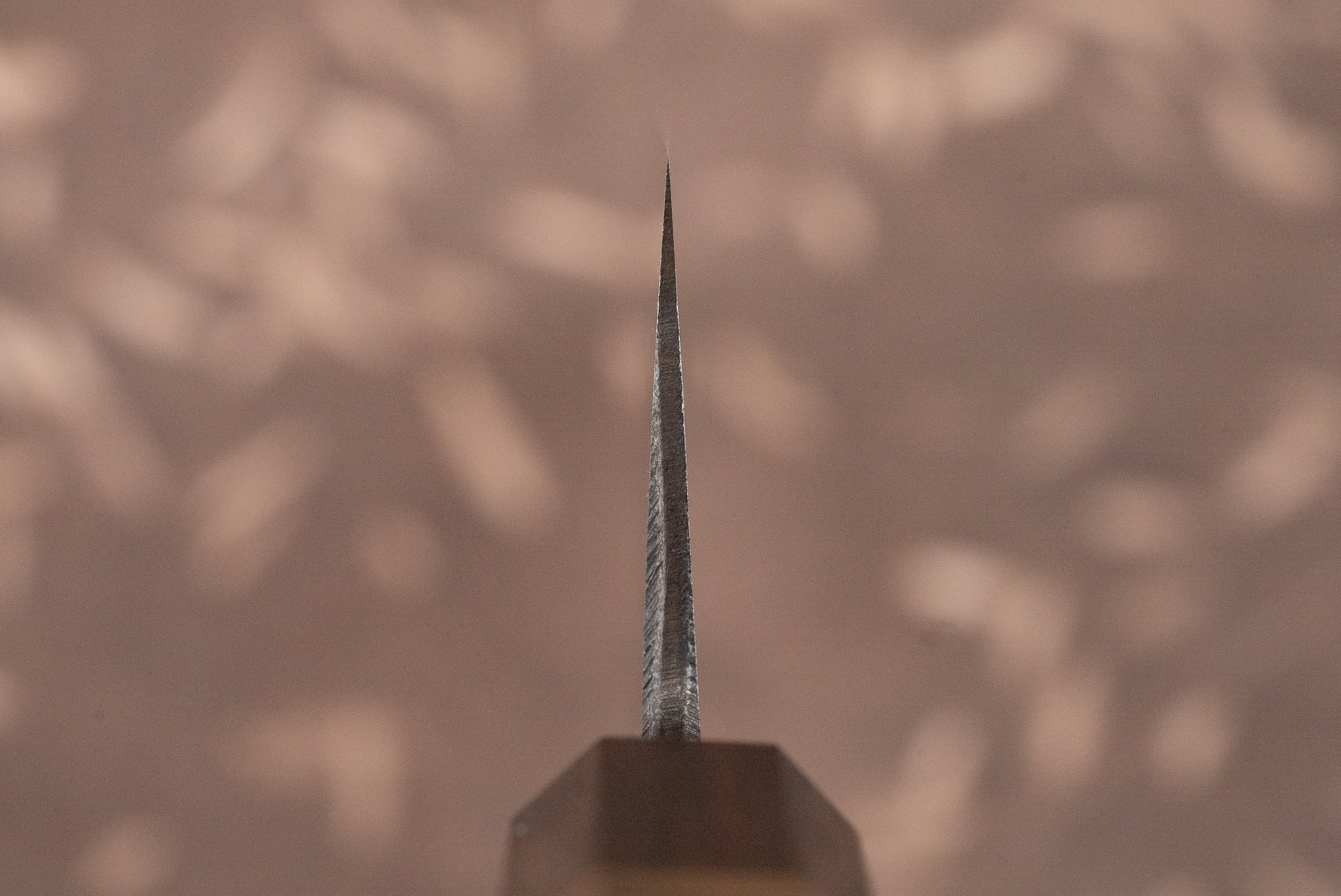 Tight close-up of the Touroku Sakai Aogami Damascus Kiritsuke Santoku 180mm knife blade edge, showcasing precision craftsmanship with its sleek design and visible handle, embodying Japanese knifemaking expertise.